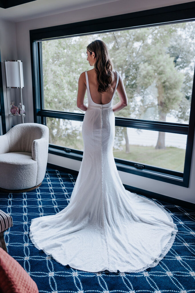 Destination wedding photographer captures bride in wedding dress standing in front of window