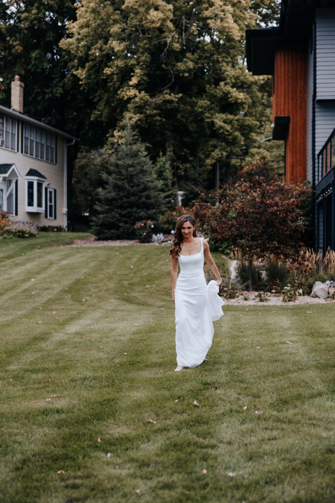 Destination wedding photographer captures bride walking across grass to meet her groom during first look