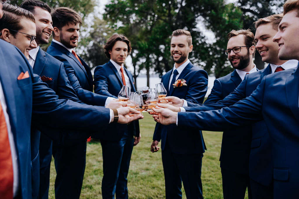 Destination wedding photographer captures groom toasting with groomsmen before romantic minnesota wedding