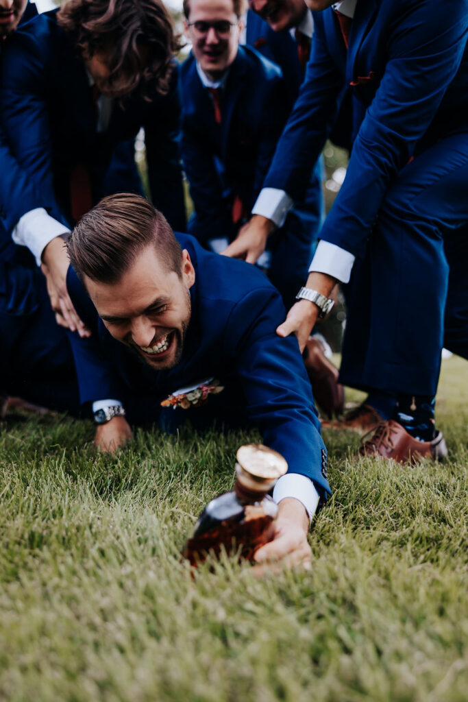 Destination wedding photographer captures groom reaching for flask