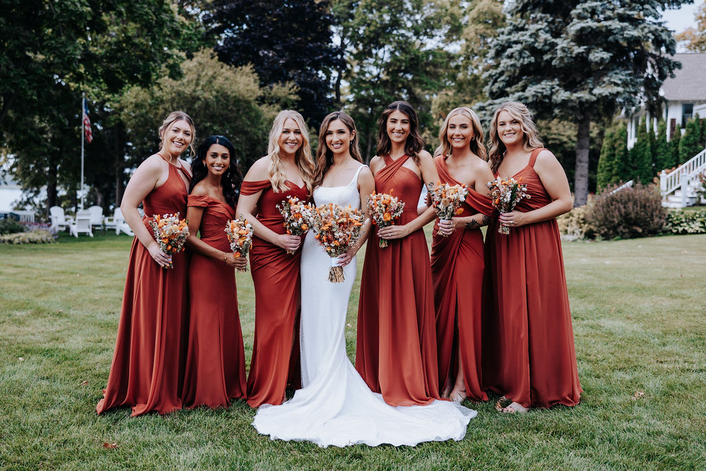 Destination wedding photographer captures bride with bridesmaids wearing rust orange dresses