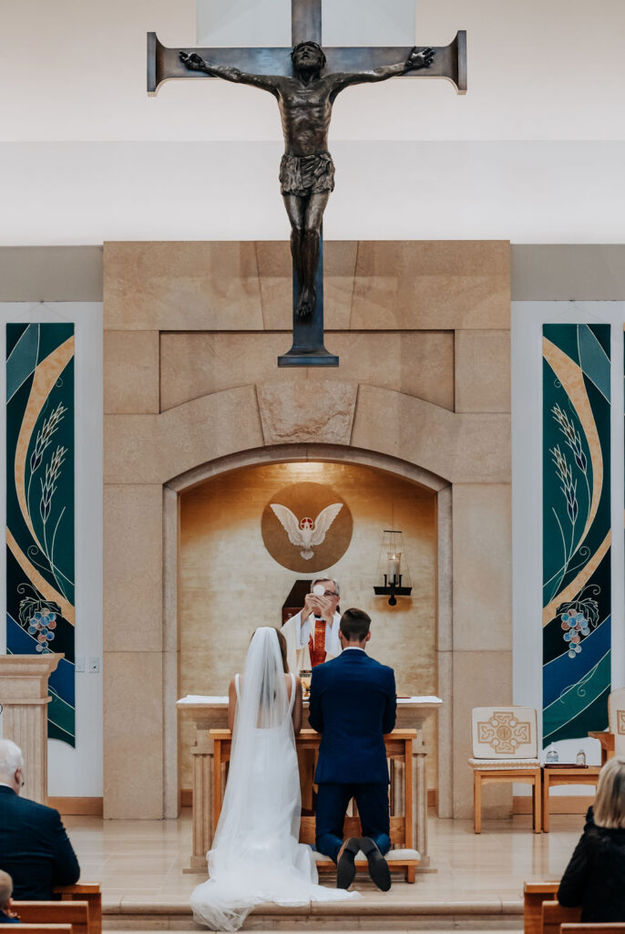 Destination wedding photographer captures bride and groom kneeling during wedding ceremony