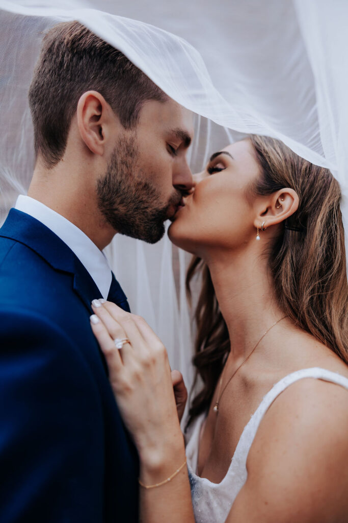 Destination wedding photographer captures bride and groom kissing under the veil