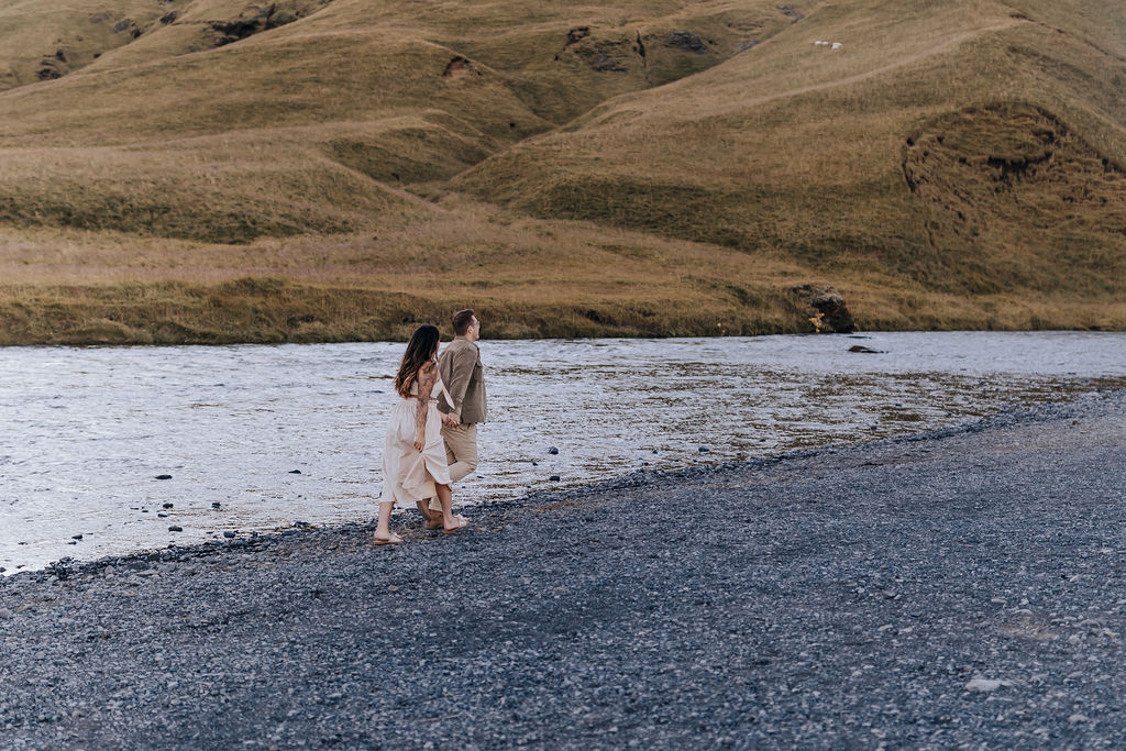 Destination wedding photographer captures engaged couple walking along beach in Iceland