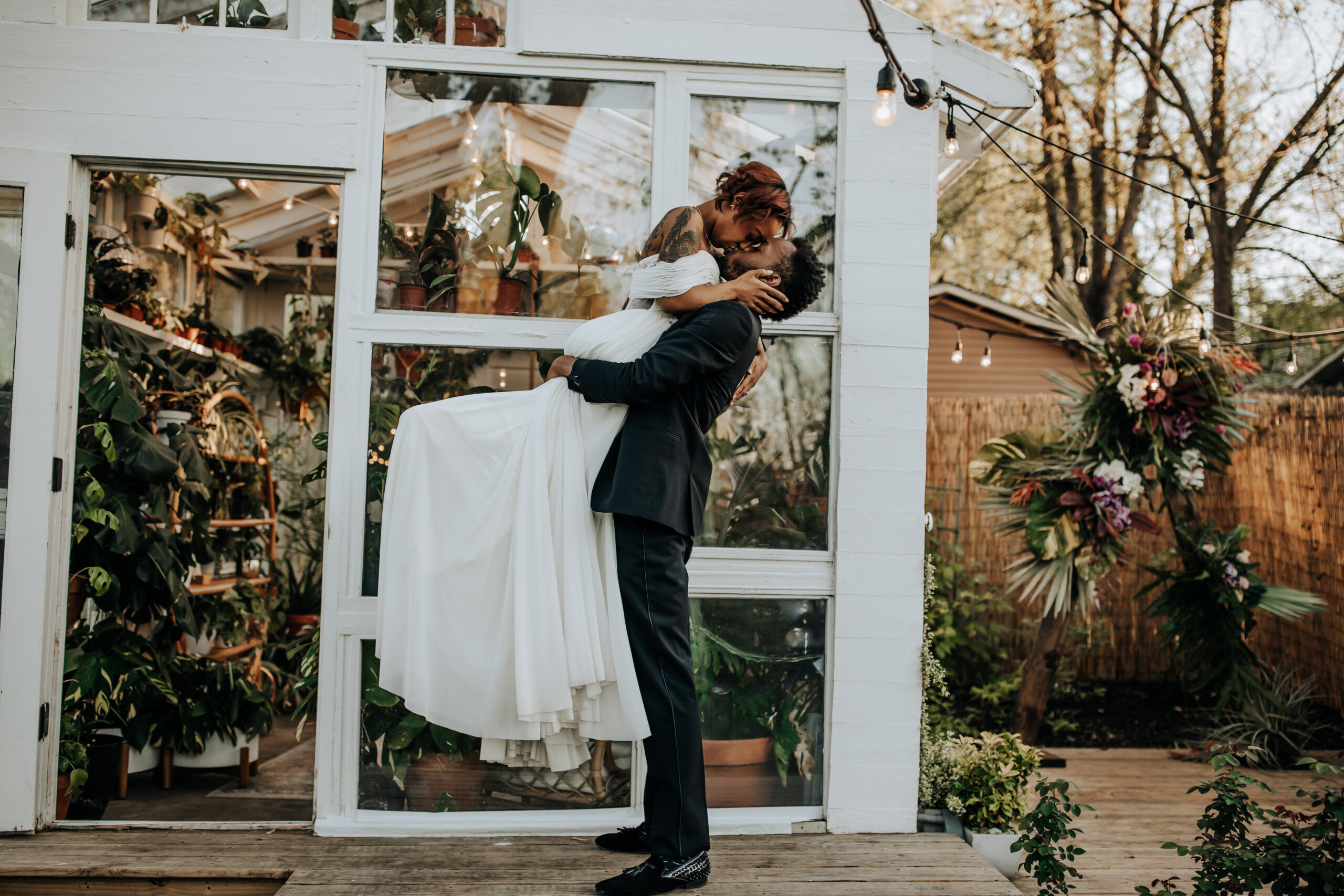 Nashville Elopement Photographer captures groom lifting bride in air and kissing her in front of East Nashville Greenhouse