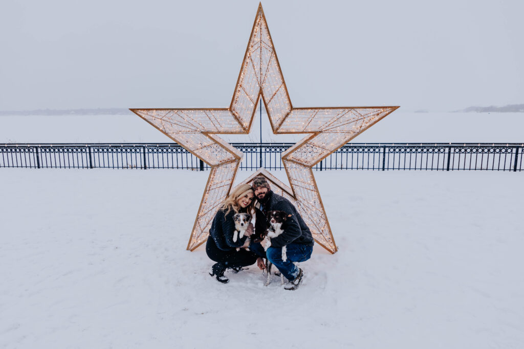 Destination Wedding Photographer captures man and woman in front of star with puppy during winter engagement photos