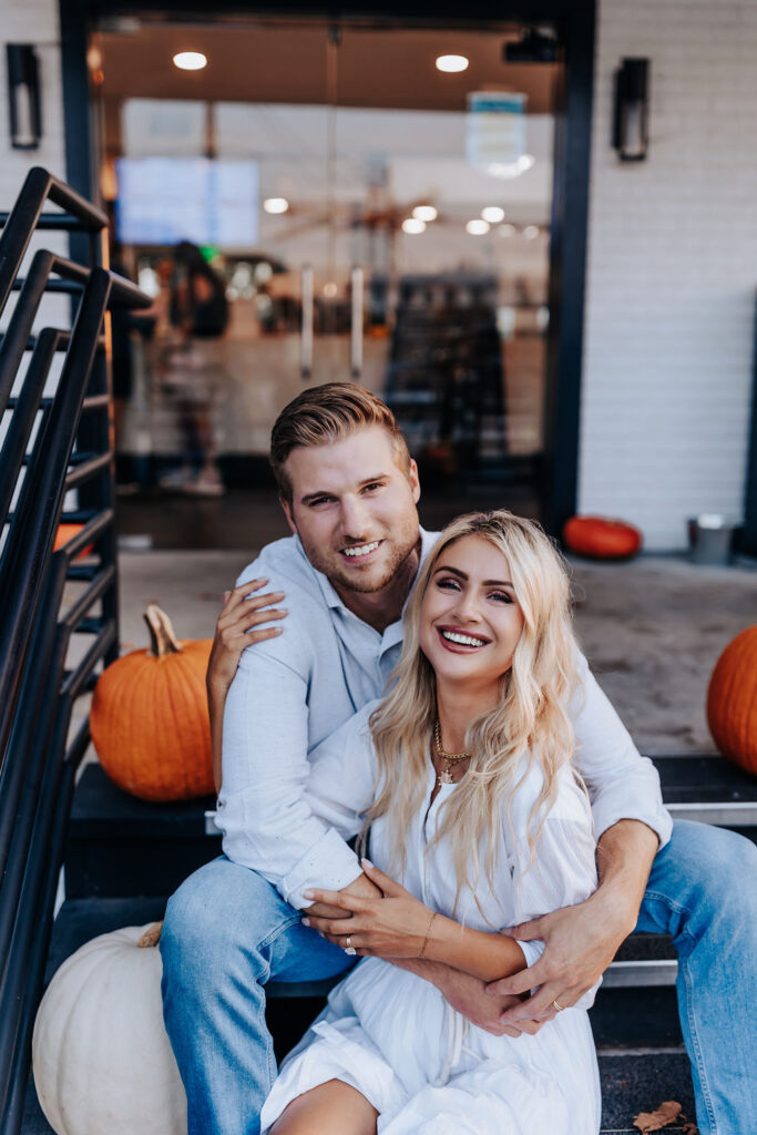 Nashville Engagement Photographer captures couple embracing on stairs surrounded by pumpkins at Wanna Spoon in Nashville