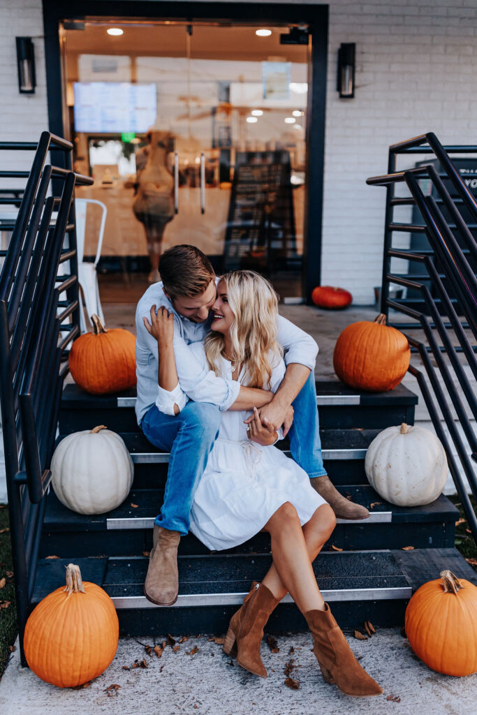 Nashville Engagement Photographer captures couple kissing on stairs surrounded by pumpkins