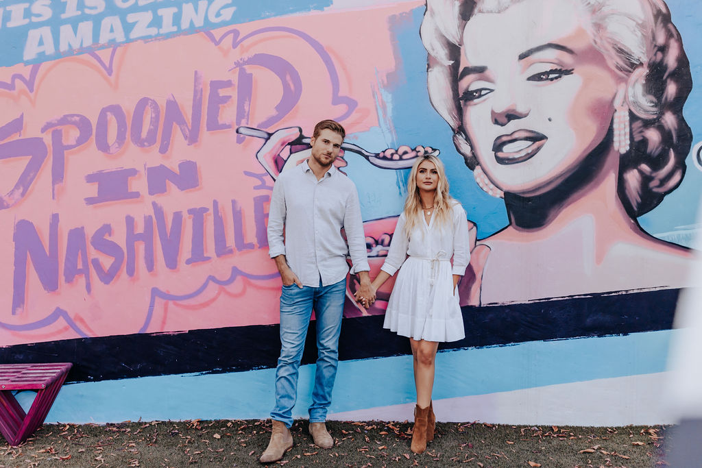 Nashville Engagement Photographer captures man and woman standing against pink wall at Wanna Spoon during Nashville date night