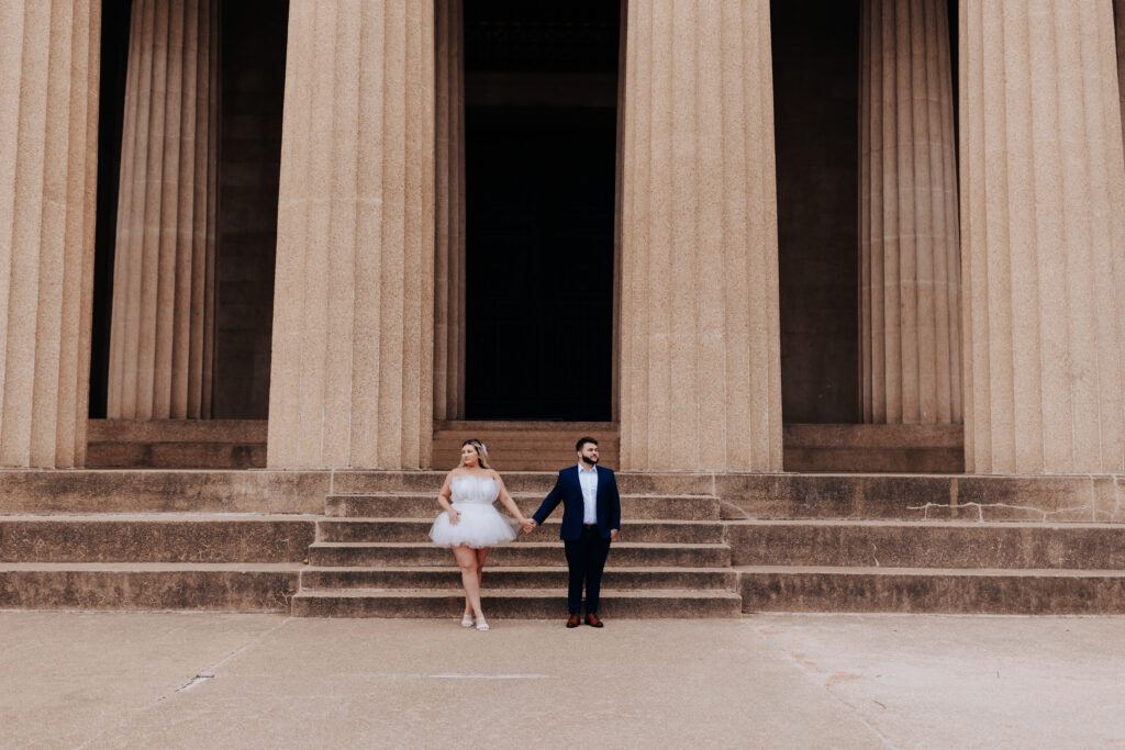 Destination Wedding Photographer captures bride and groom holding hands at the parthenon in Nashville