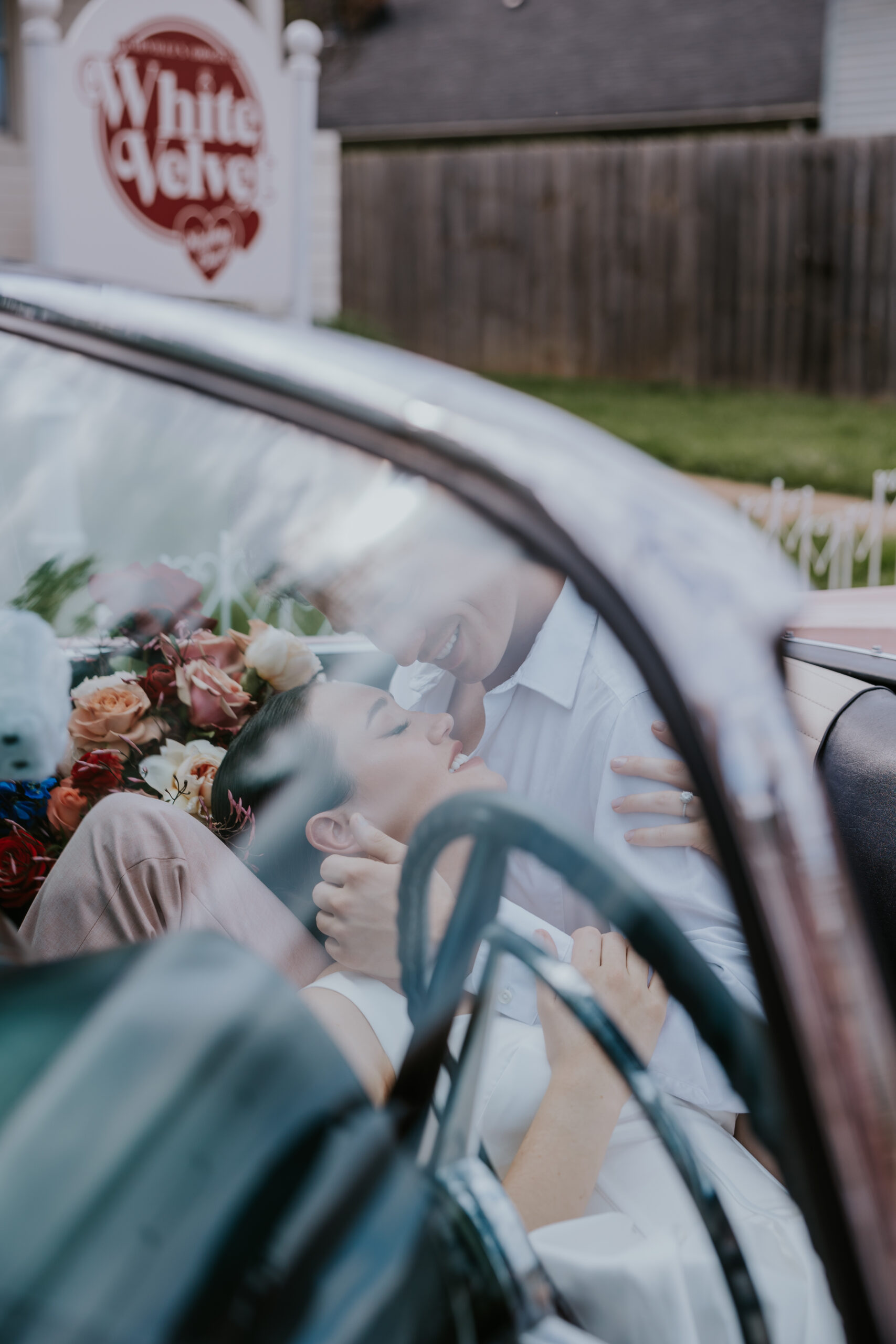 Playful wedding moment of a couple kissing in a vintage car filled with florals, captured at one of the trendiest places to get married in Nashville TN.