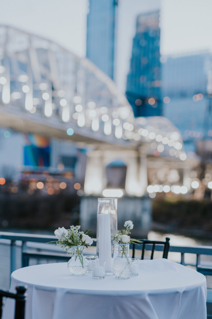 Outdoor wedding tablescapes with bridge building and Nashville skyline in background