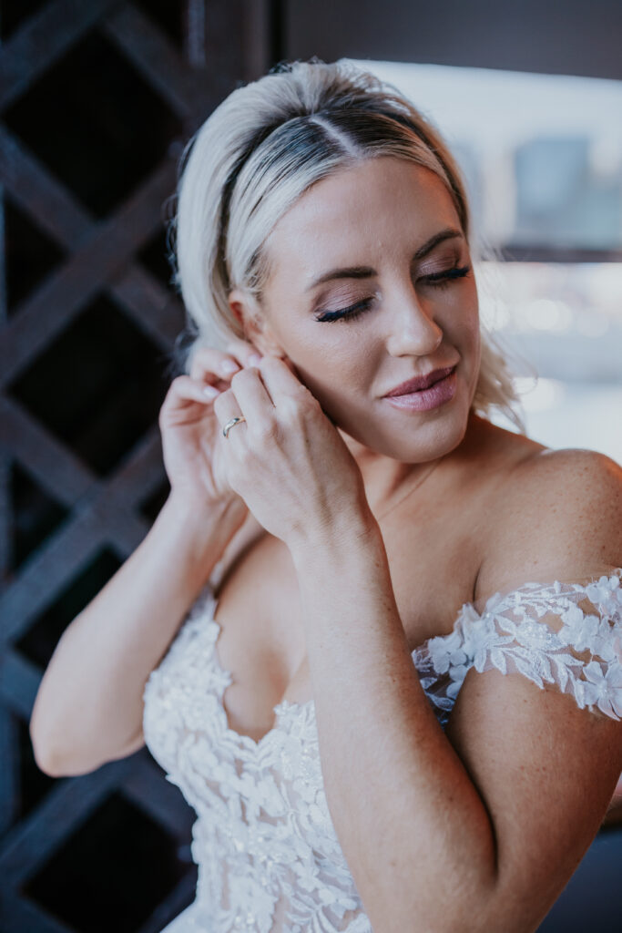 bride putting on earrings before classic and chic Bridge Building wedding
