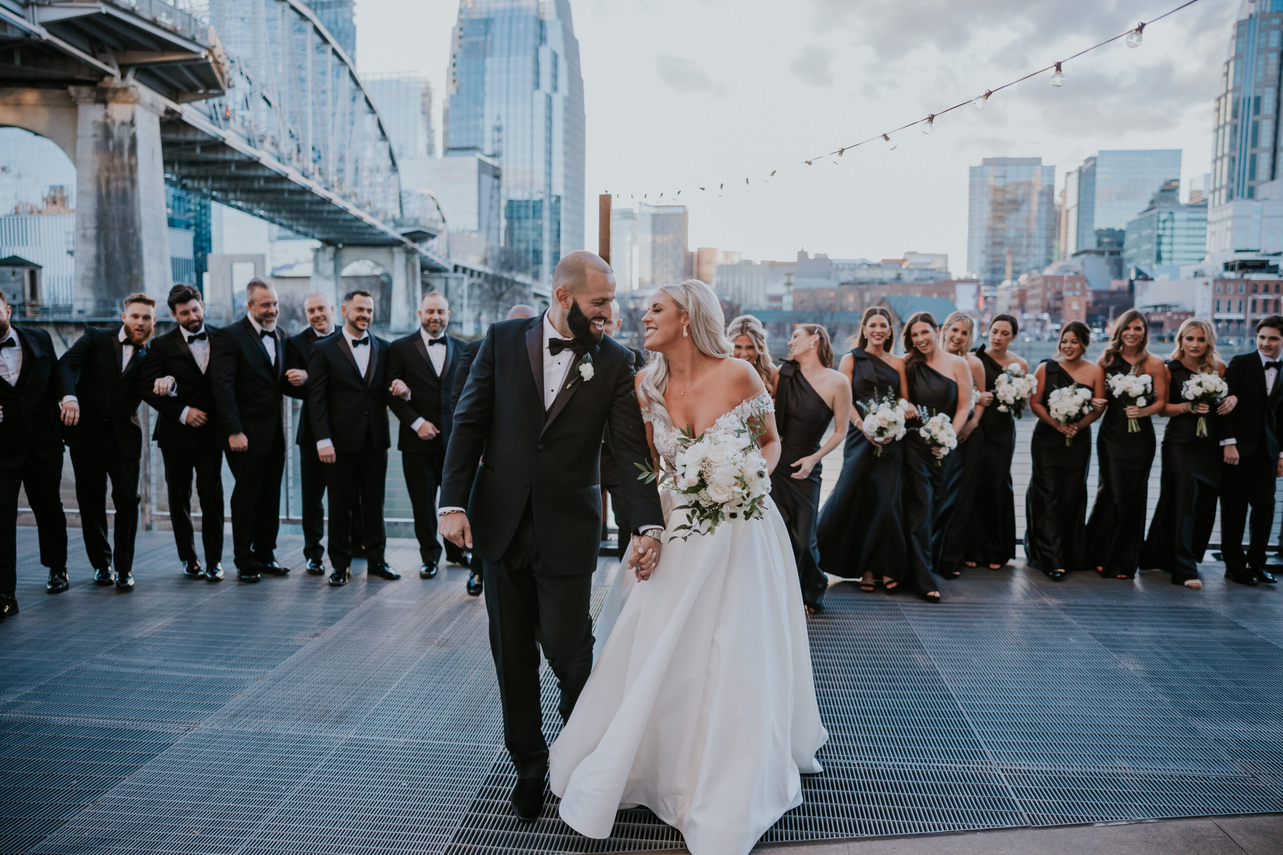 bride and groom celebrating with wedding party walking behind them