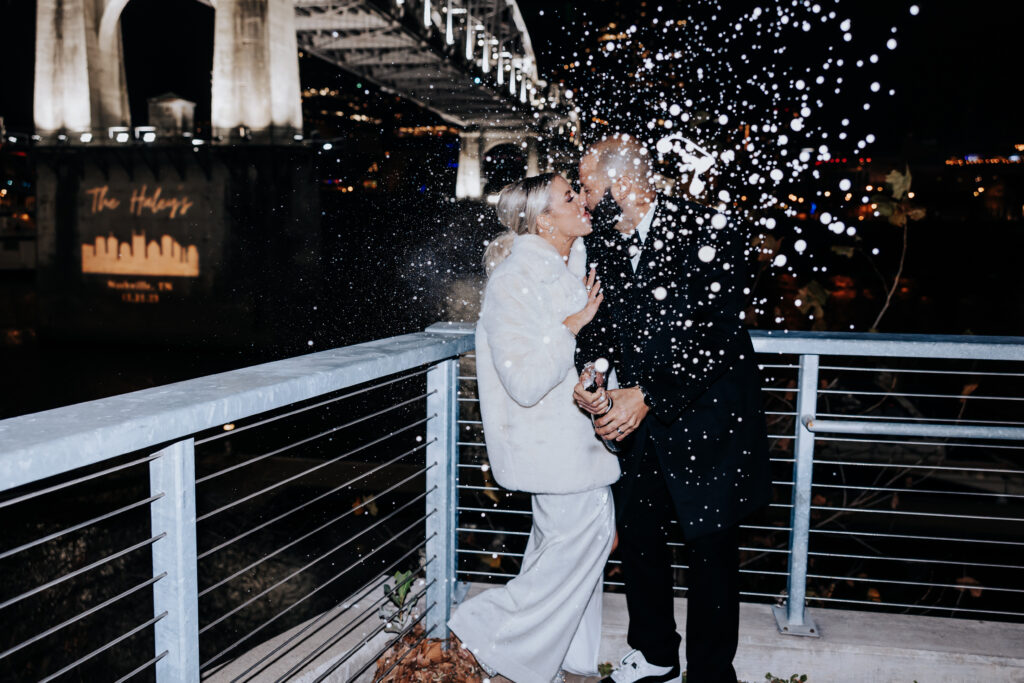 bride and groom popping champagne and kissing