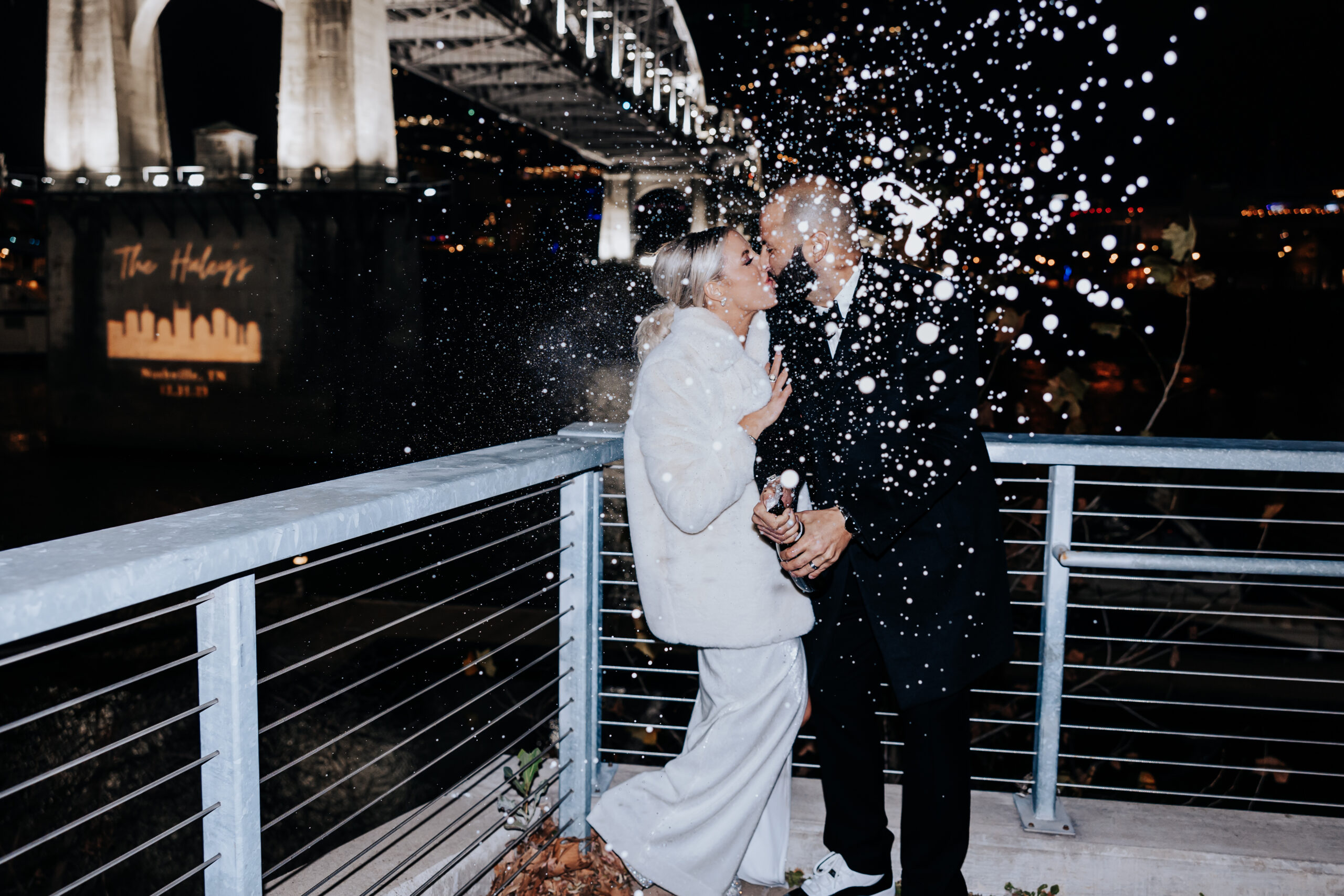 bride and groom popping champagne and kissing