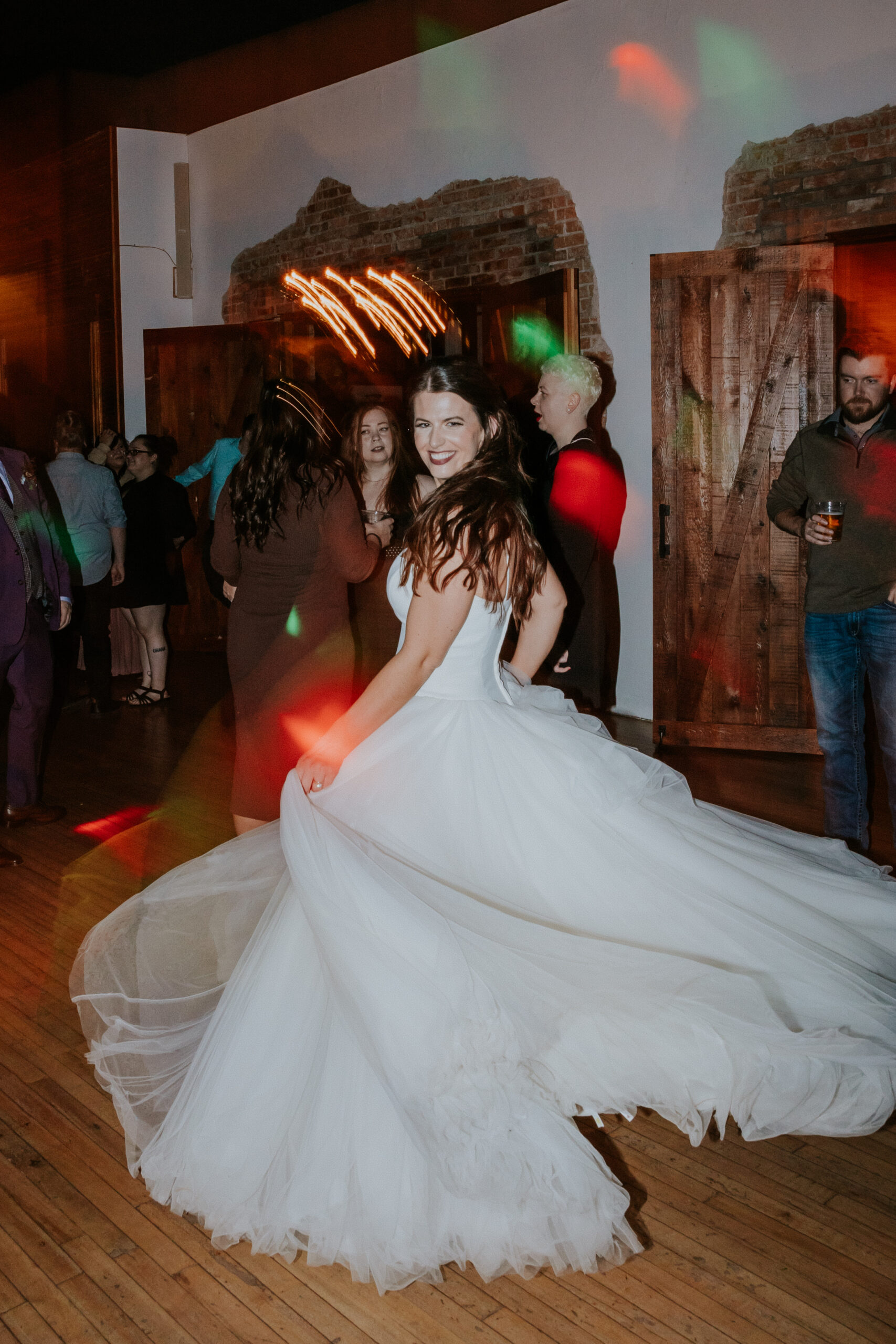 Bride spinning in her tulle wedding dress on the dance floor, laughing mid-reception.