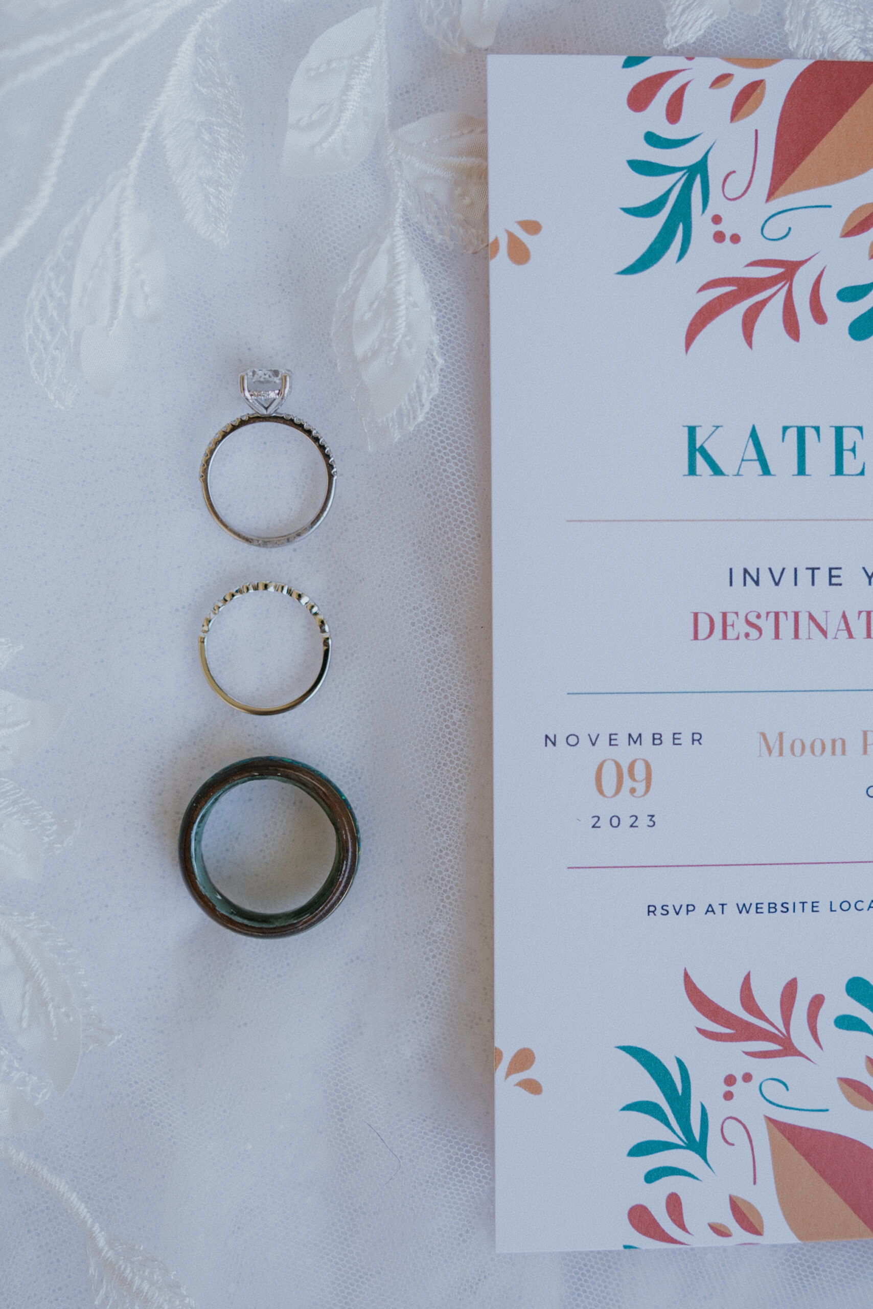 Wedding invitation and three rings arranged neatly on white lace, highlighting elegant details for a Mexico destination wedding.