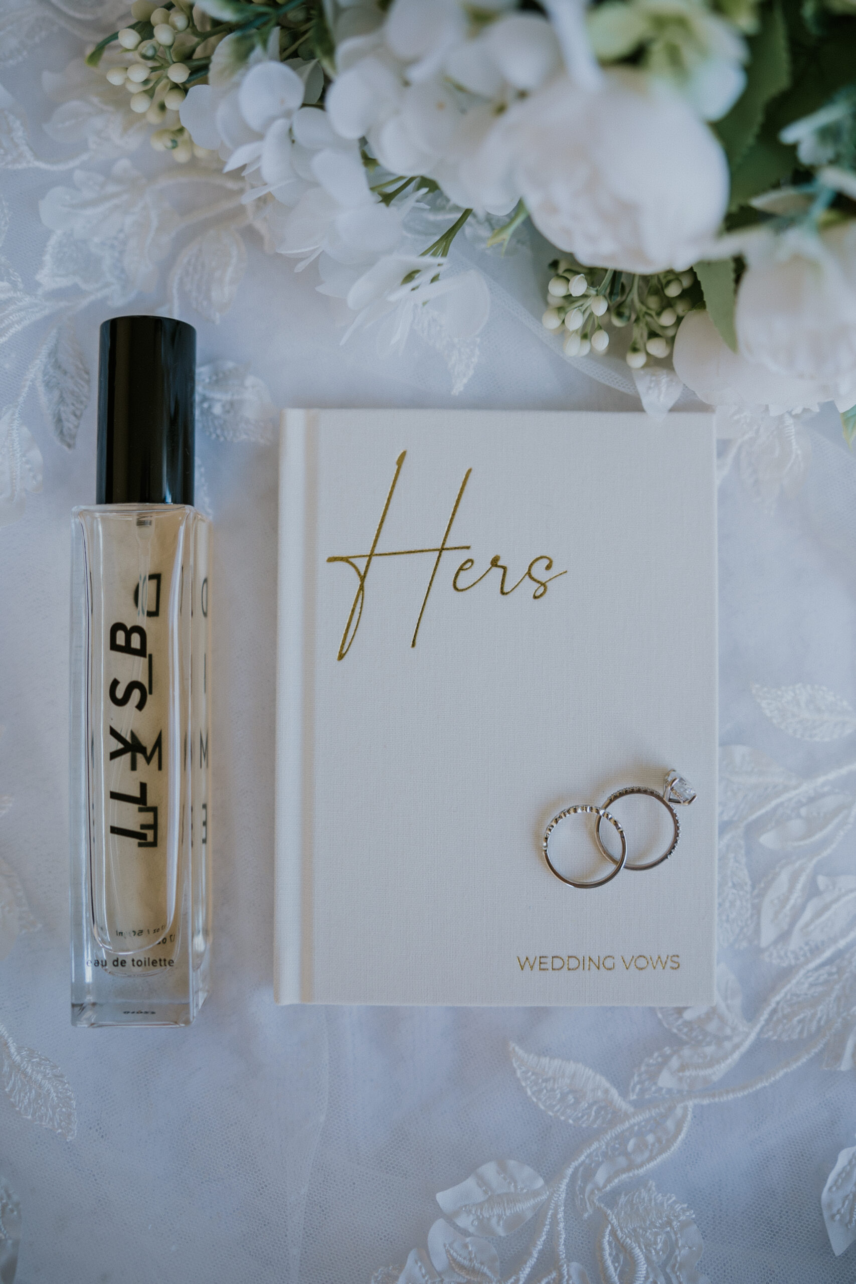 Flat lay of the bride’s vow book with rings, perfume, and florals — elegant details for a Mexico destination wedding.