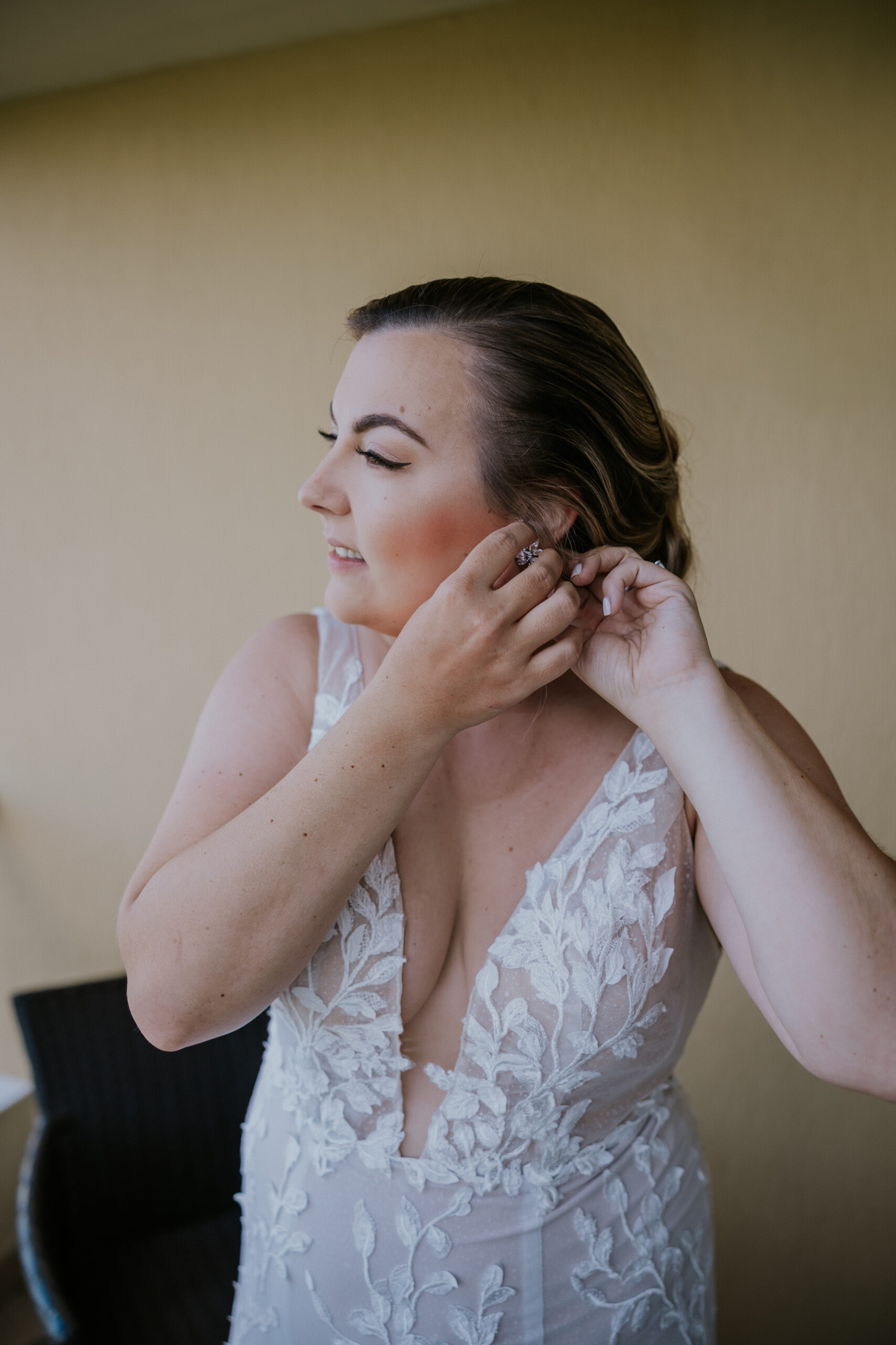 Bride puts on sparkly drop earrings as she finishes getting ready in her bridal suite.