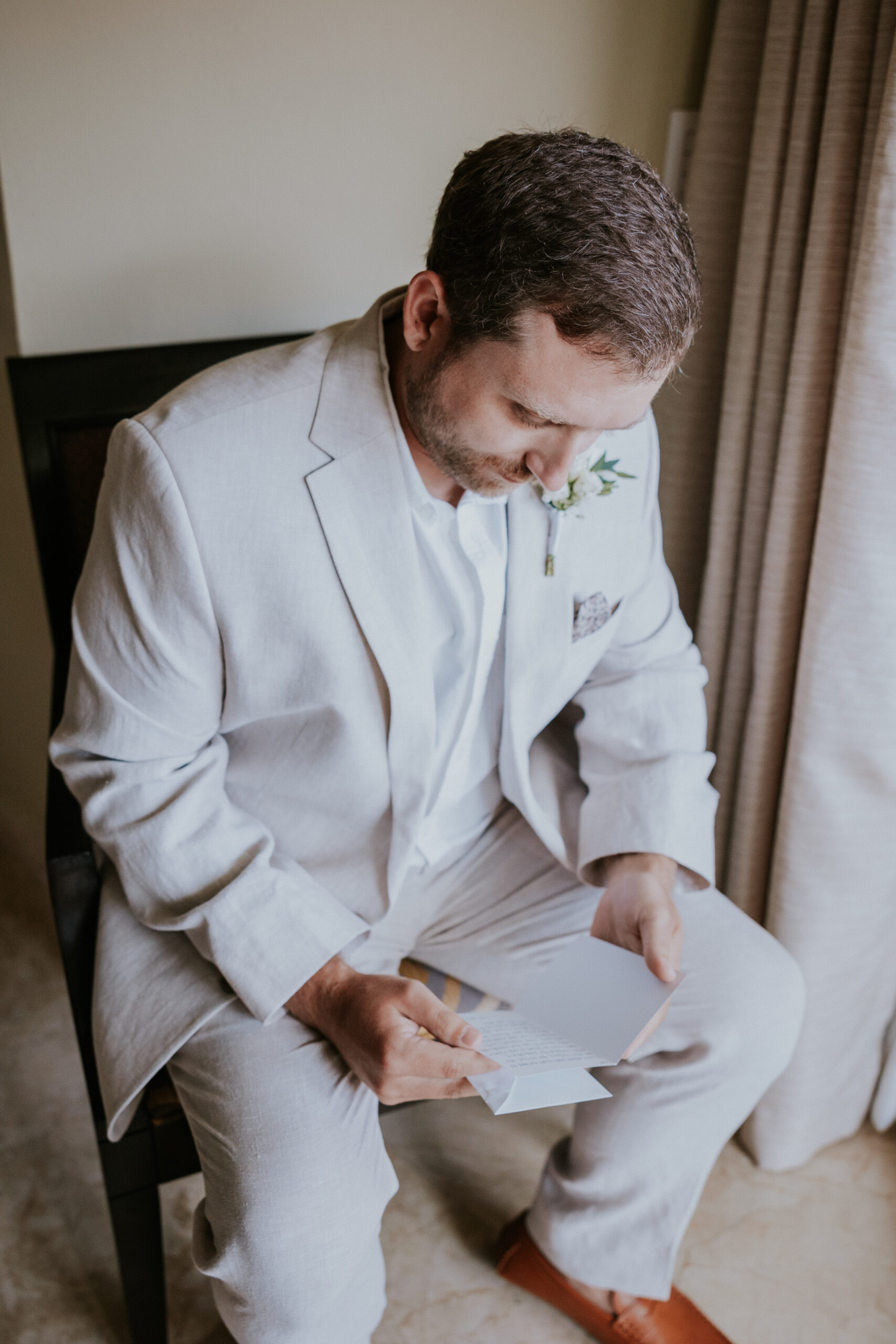 Groom sits quietly by the window, reading a letter from his bride on the morning of their Mexico destination wedding.