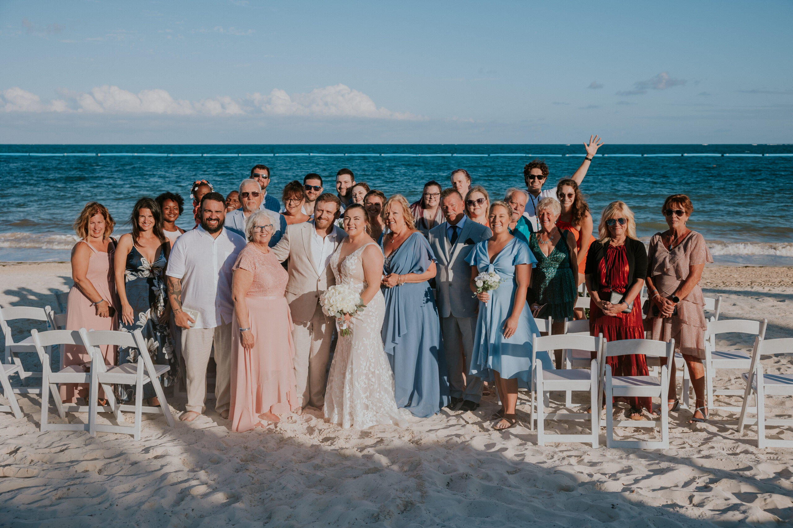 Group photo of wedding guests and family celebrating on the beach at a Mexico destination wedding.