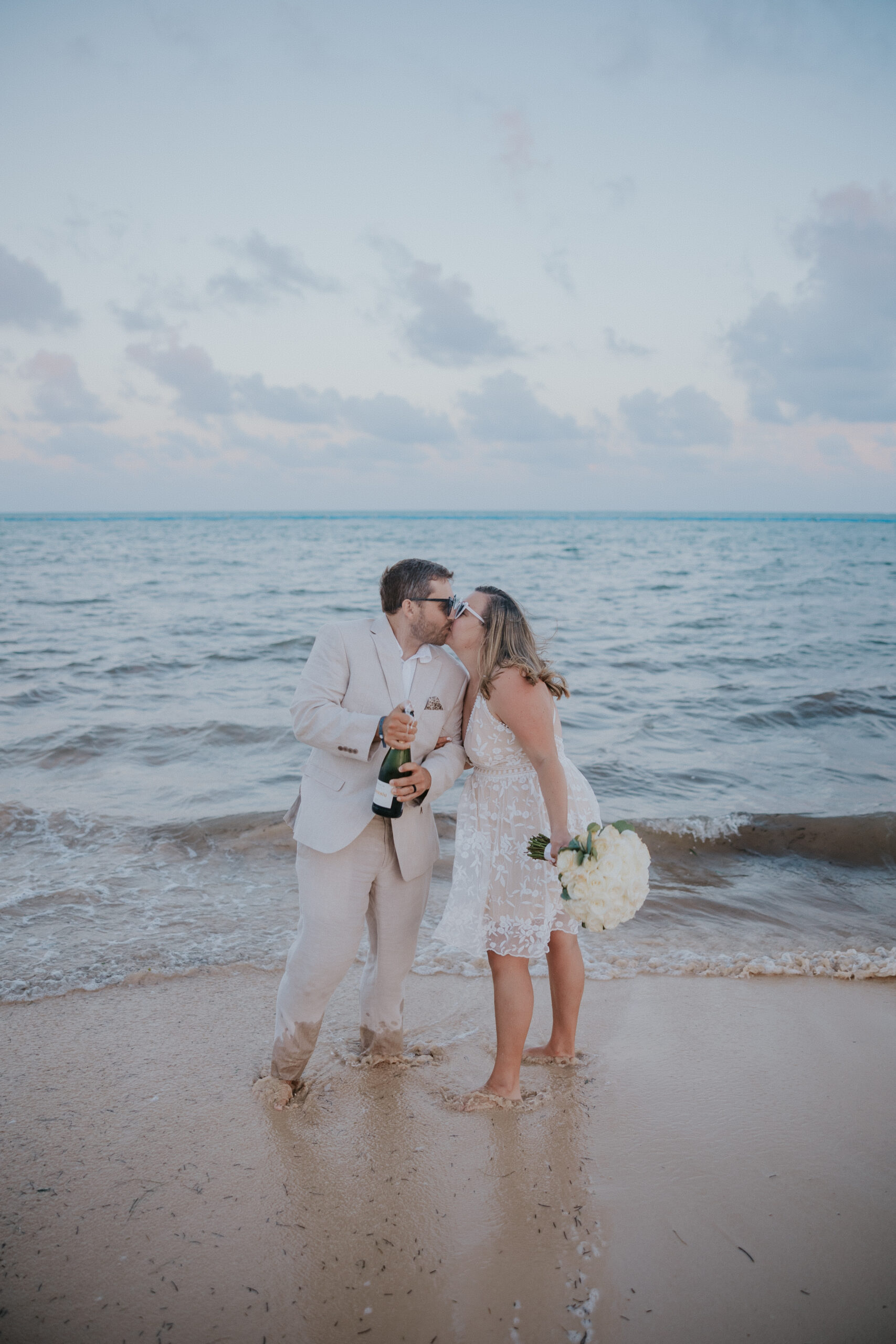 Bride and groom giving a toast with champagne glasses during their Mexico destination wedding.