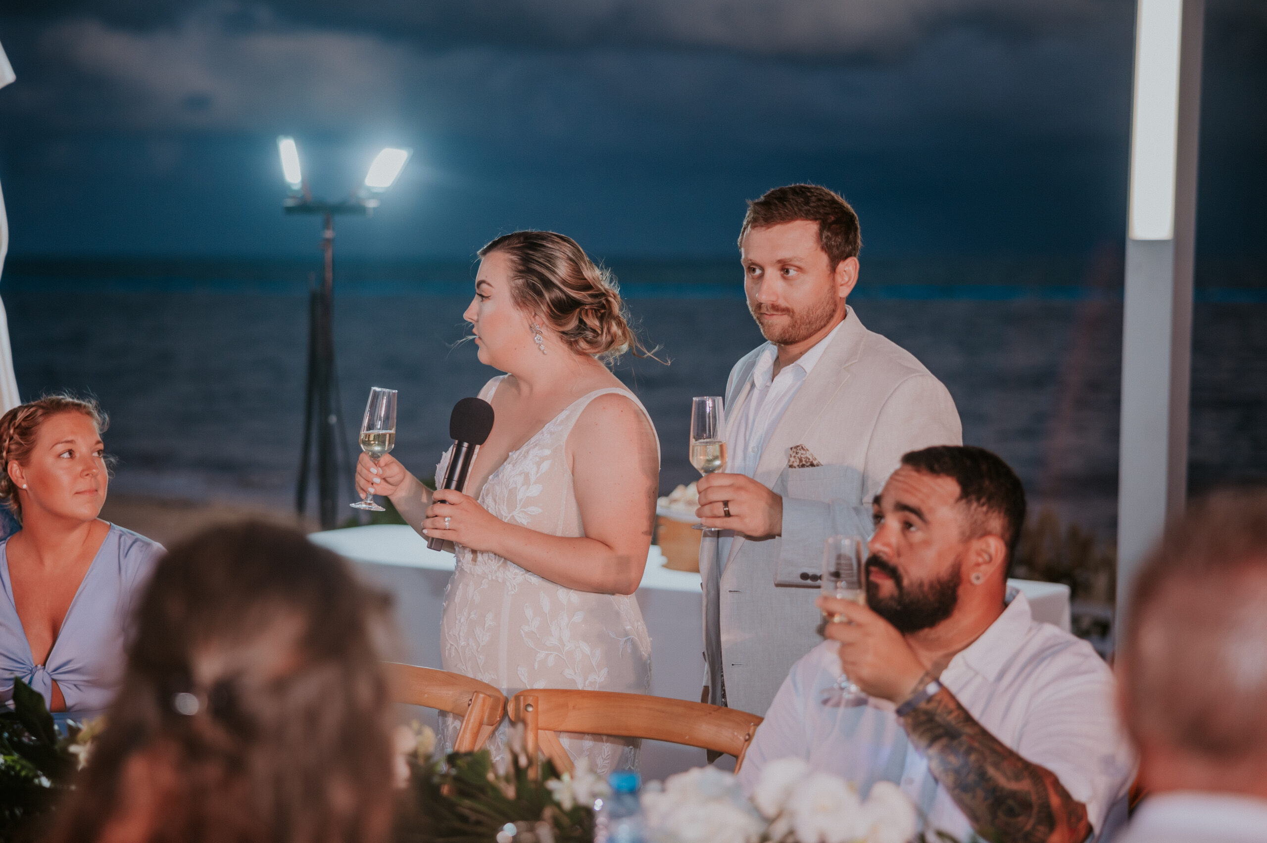 Family and friends enjoying dinner and drinks at an outdoor beach reception.