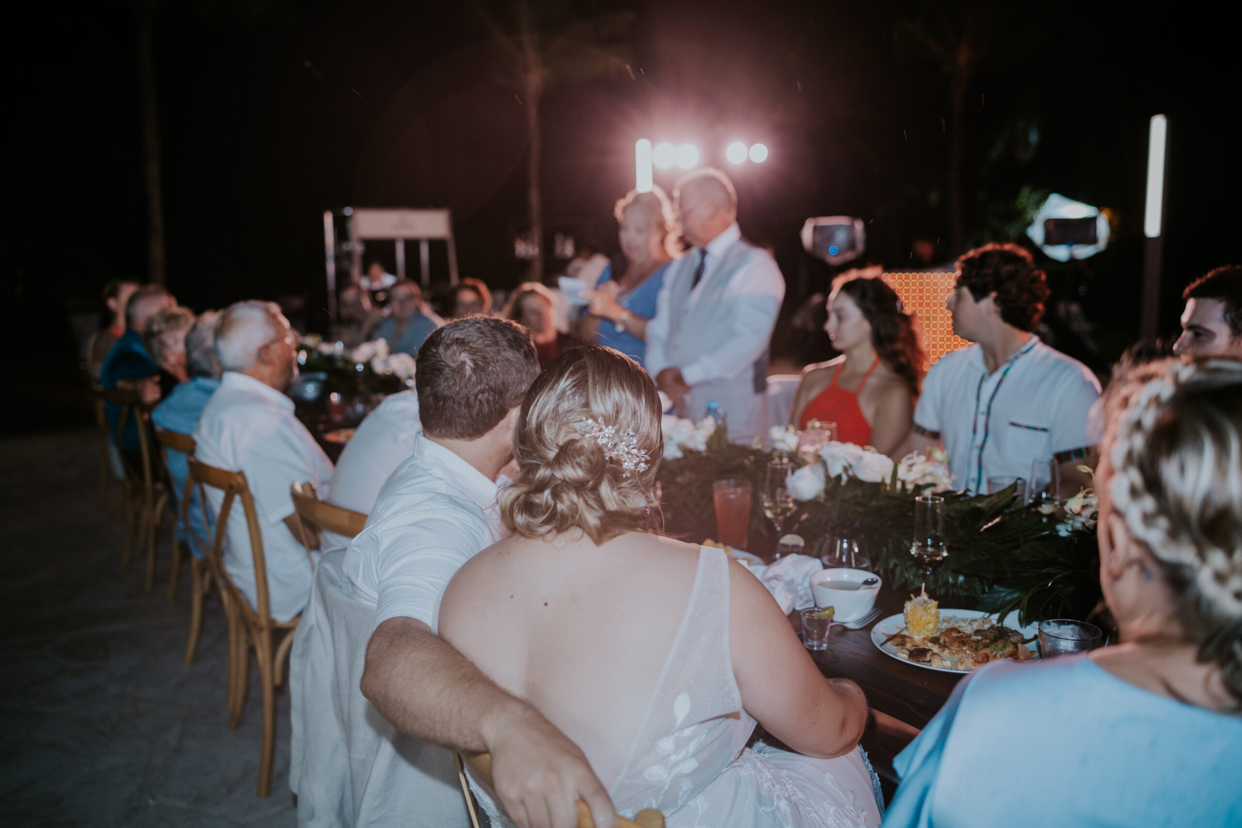 Bride and groom sitting barefoot on the sand surrounded by lush floral arrangements during their Mexico destination wedding.