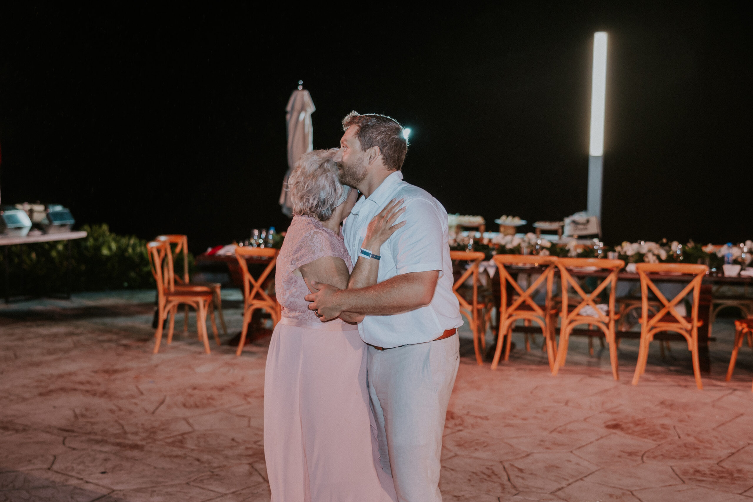 Groom sharing a sweet dance with a family member under the night sky at their Mexico destination wedding.