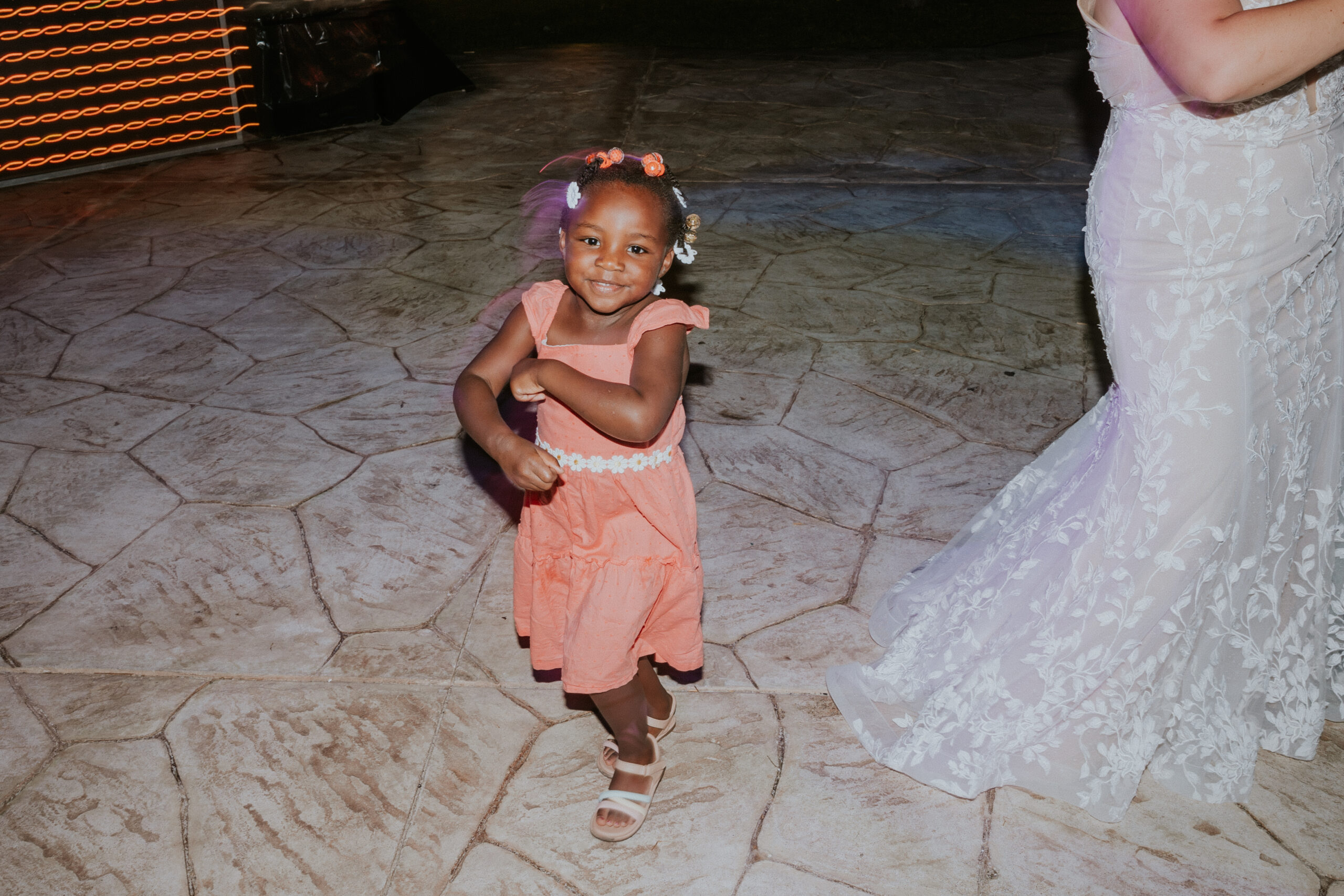 Young flower girl twirling and dancing at the outdoor wedding reception.