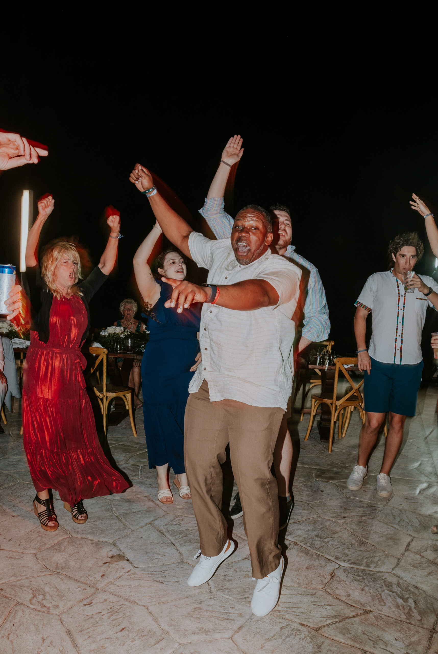 Wedding guests raising their hands and celebrating on the dance floor.