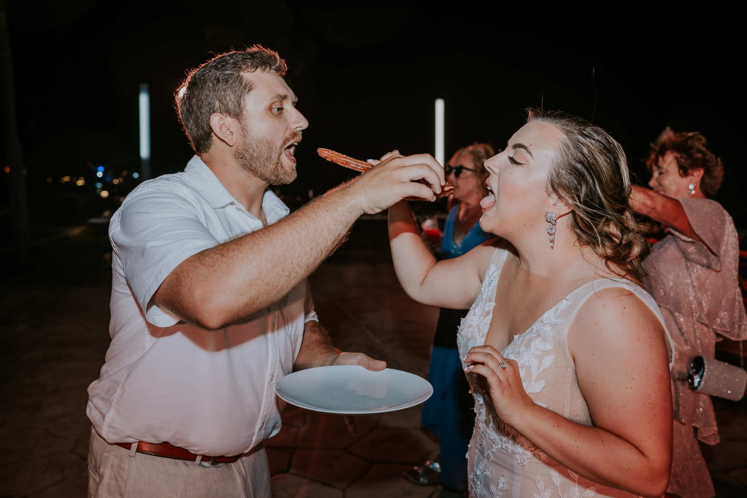 Bride and groom sharing a churro together during their Mexico destination wedding reception.