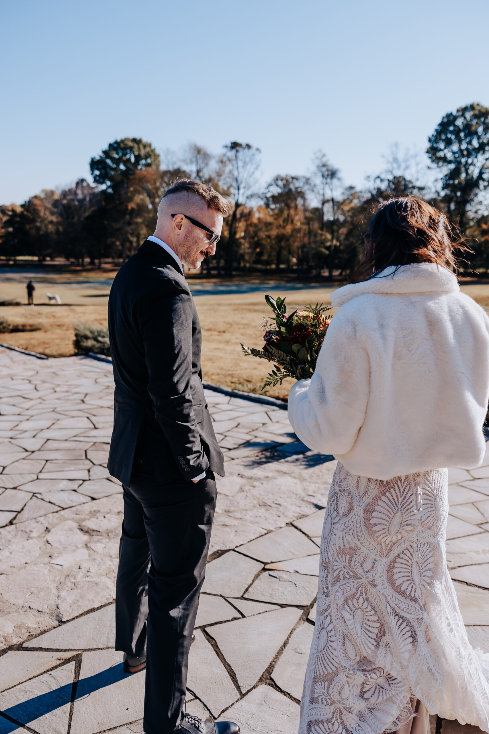Bride and groom sharing a private moment before the ceremony begins, surrounded by golden leaves and clear blue skies.