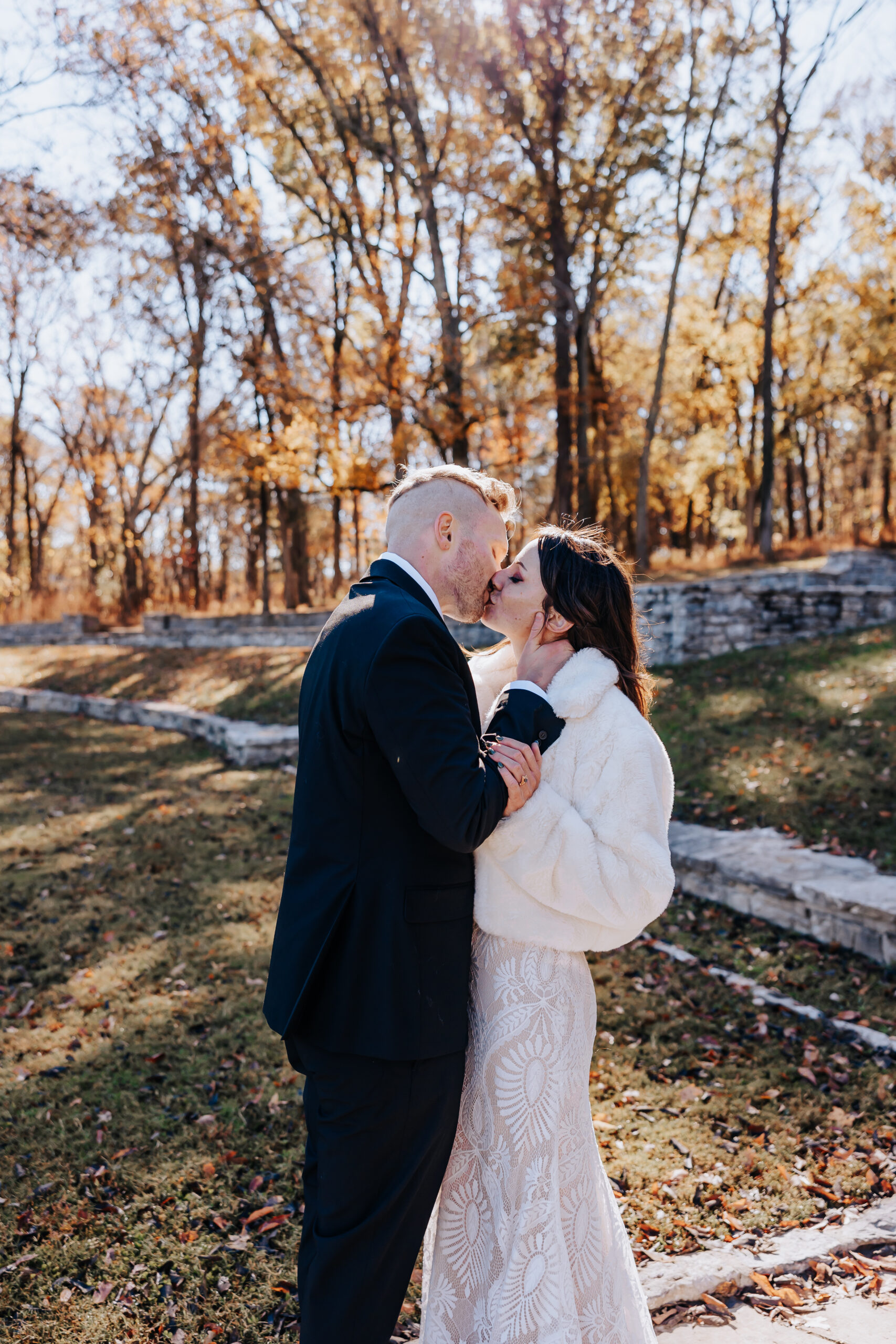 A quiet, tender kiss between bride and groom, surrounded by the warmth of fall foliage during their wedding in Nashville.