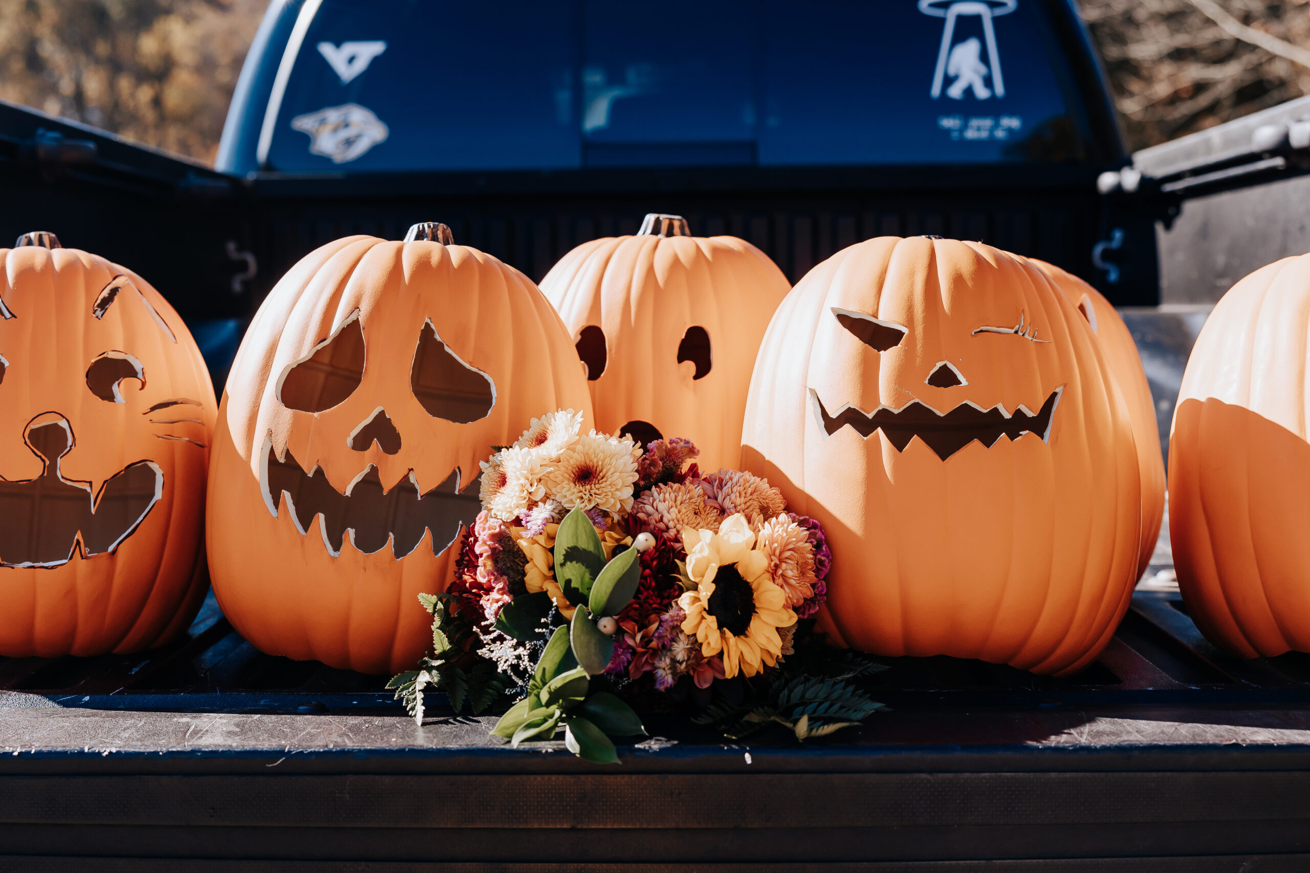 Fall bouquet resting beside a row of carved pumpkins in the back of a pickup truck, capturing festive wedding details in Nashville.