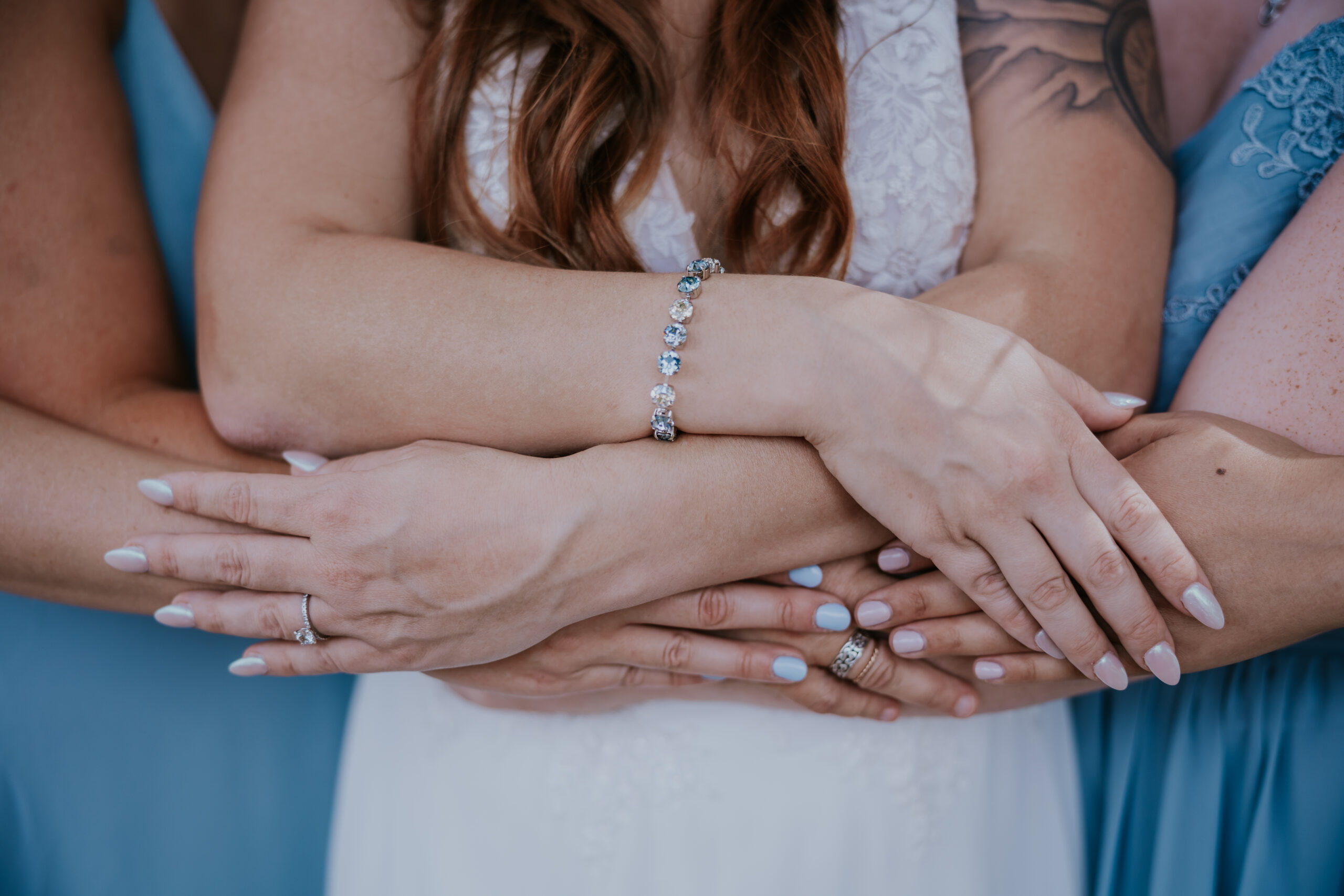 A heartfelt embrace of hands between the bride and bridesmaids, highlighting delicate rings and a sparkling bracelet — a sweet moment inspired by unique wedding ideas focused on connection.