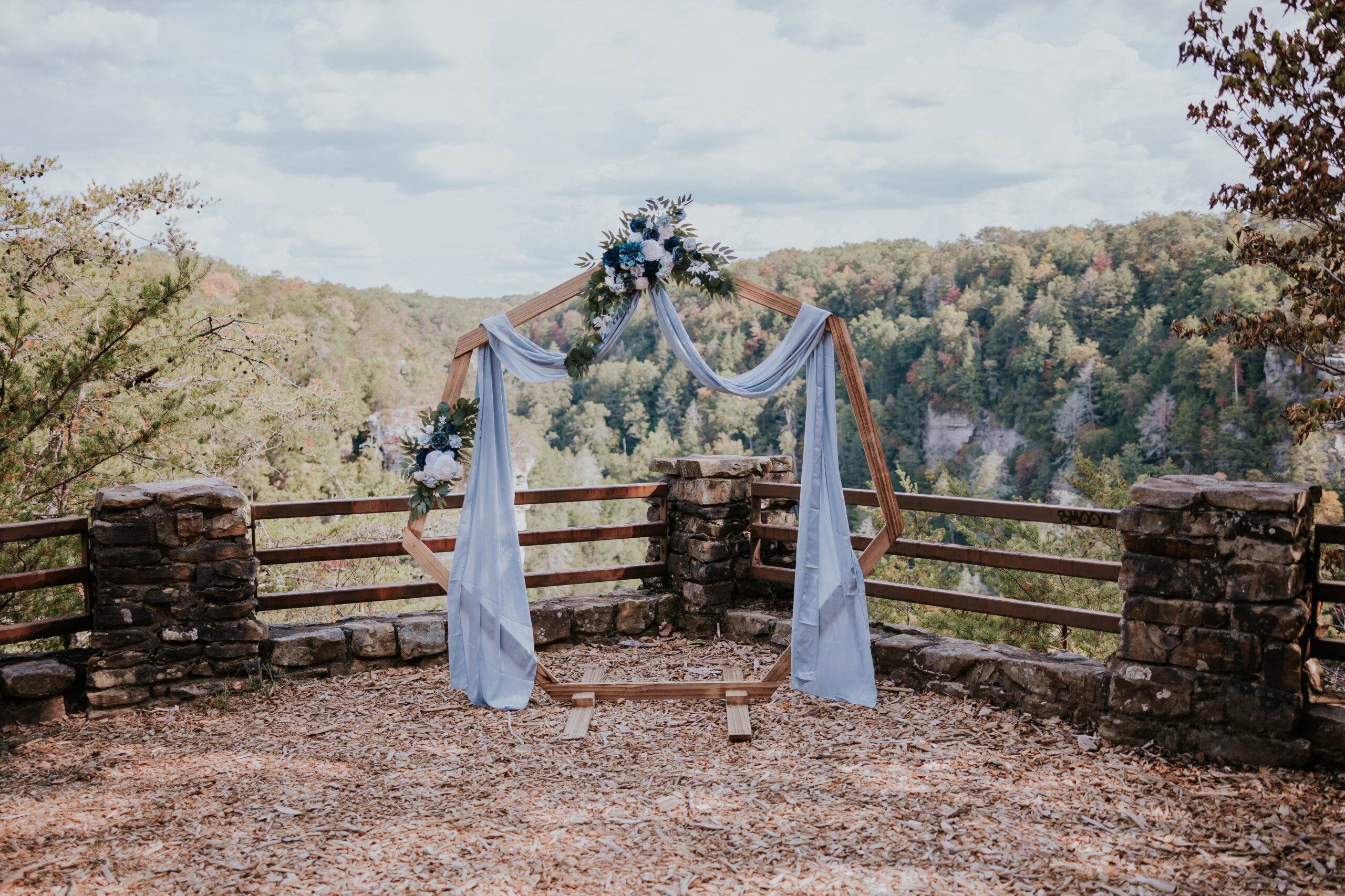Geometric wooden arbor draped in soft blue fabric and florals at an epic cliffside overlook — a stunning backdrop for couples seeking unique wedding ideas in Tennessee.