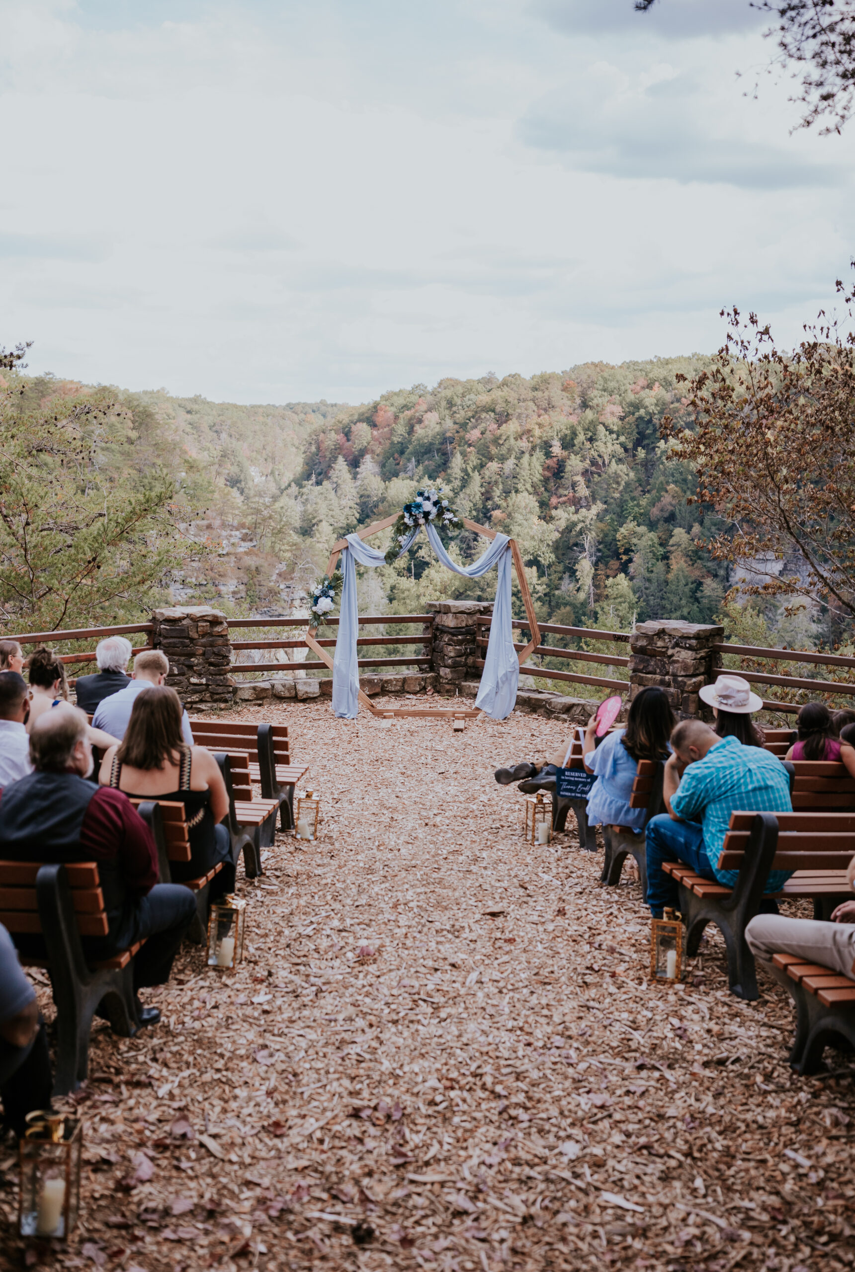 Guests seated for a scenic outdoor ceremony overlooking the mountains at Fall Creek Falls, featuring a woodchip aisle and floral-draped arbor — a perfect example of unique wedding ideas in nature.
