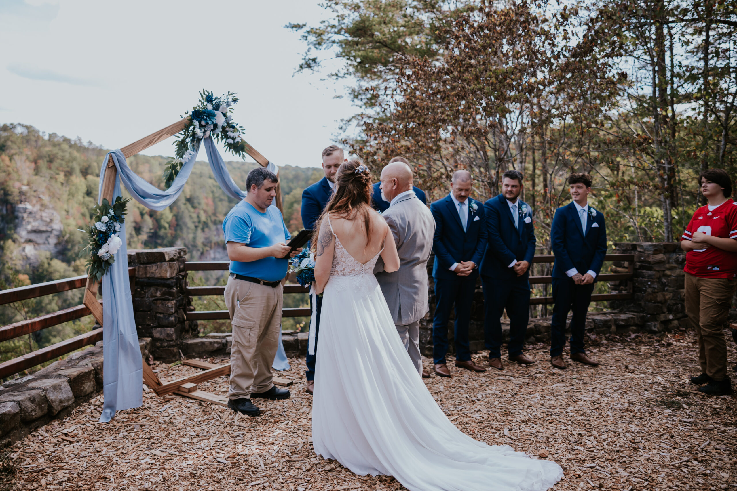 The couple stands side-by-side as the officiant prepares for vows, overlooking a stunning Tennessee cliffside — a gorgeous take on unique wedding ideas in nature.