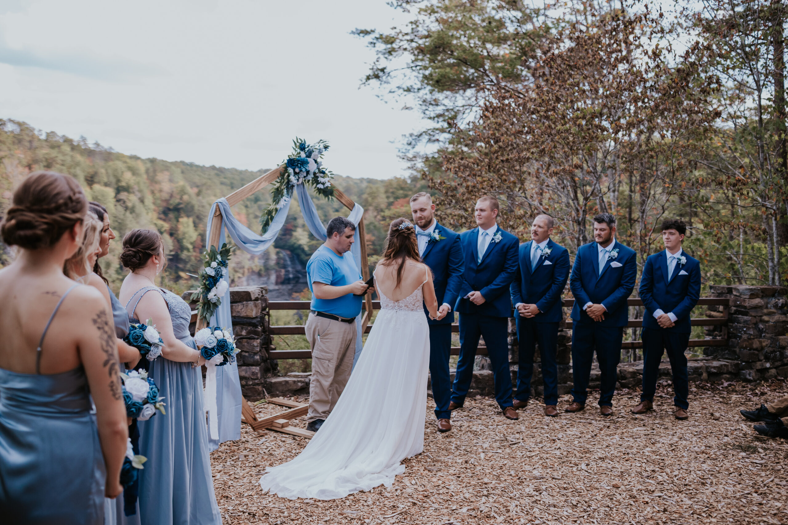 Bride and groom exchange vows at a scenic overlook ceremony at Fall Creek Falls, surrounded by their bridal party in soft blue tones.