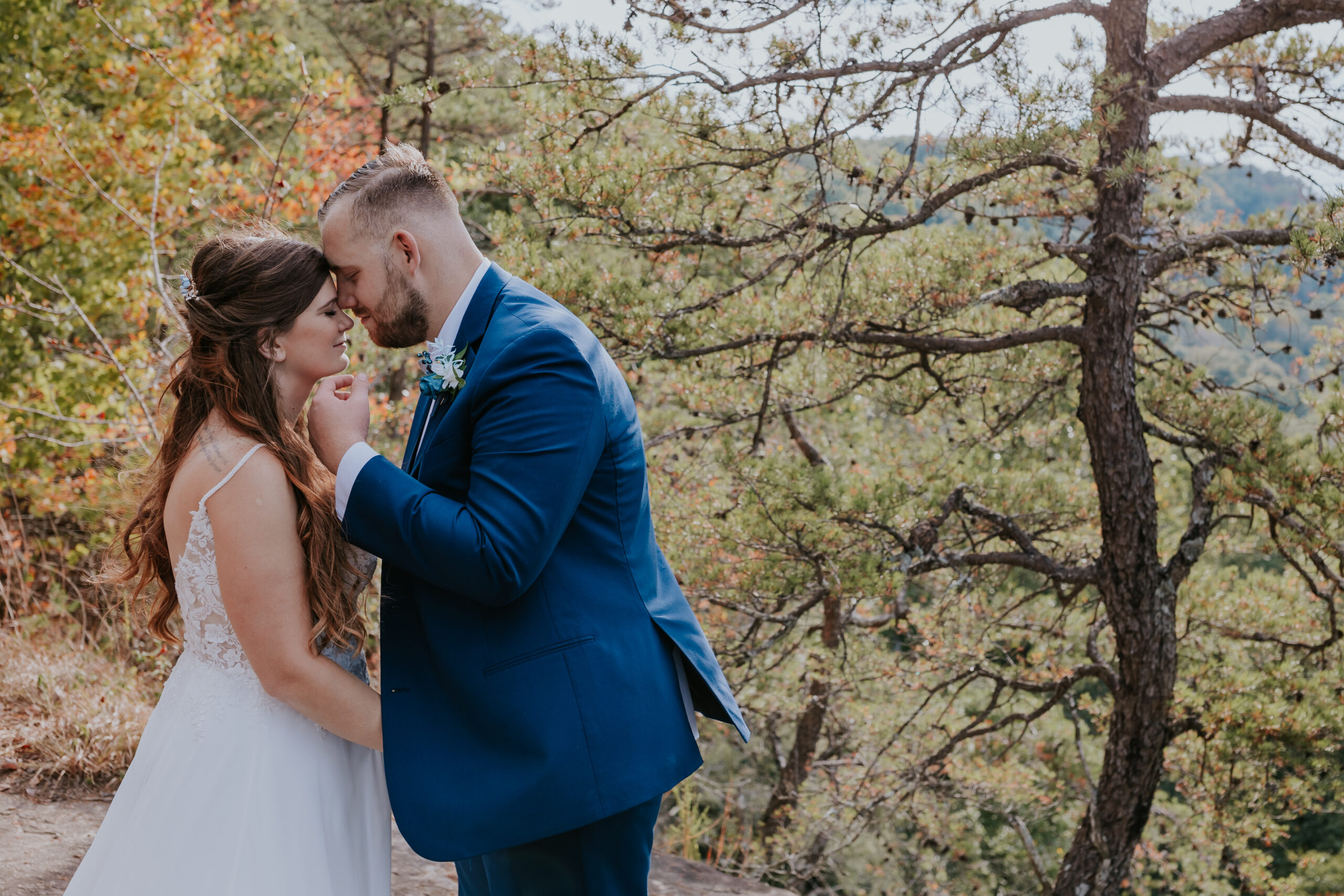 Bride and groom share a tender moment with foreheads touching, surrounded by golden autumn trees in Tennessee.