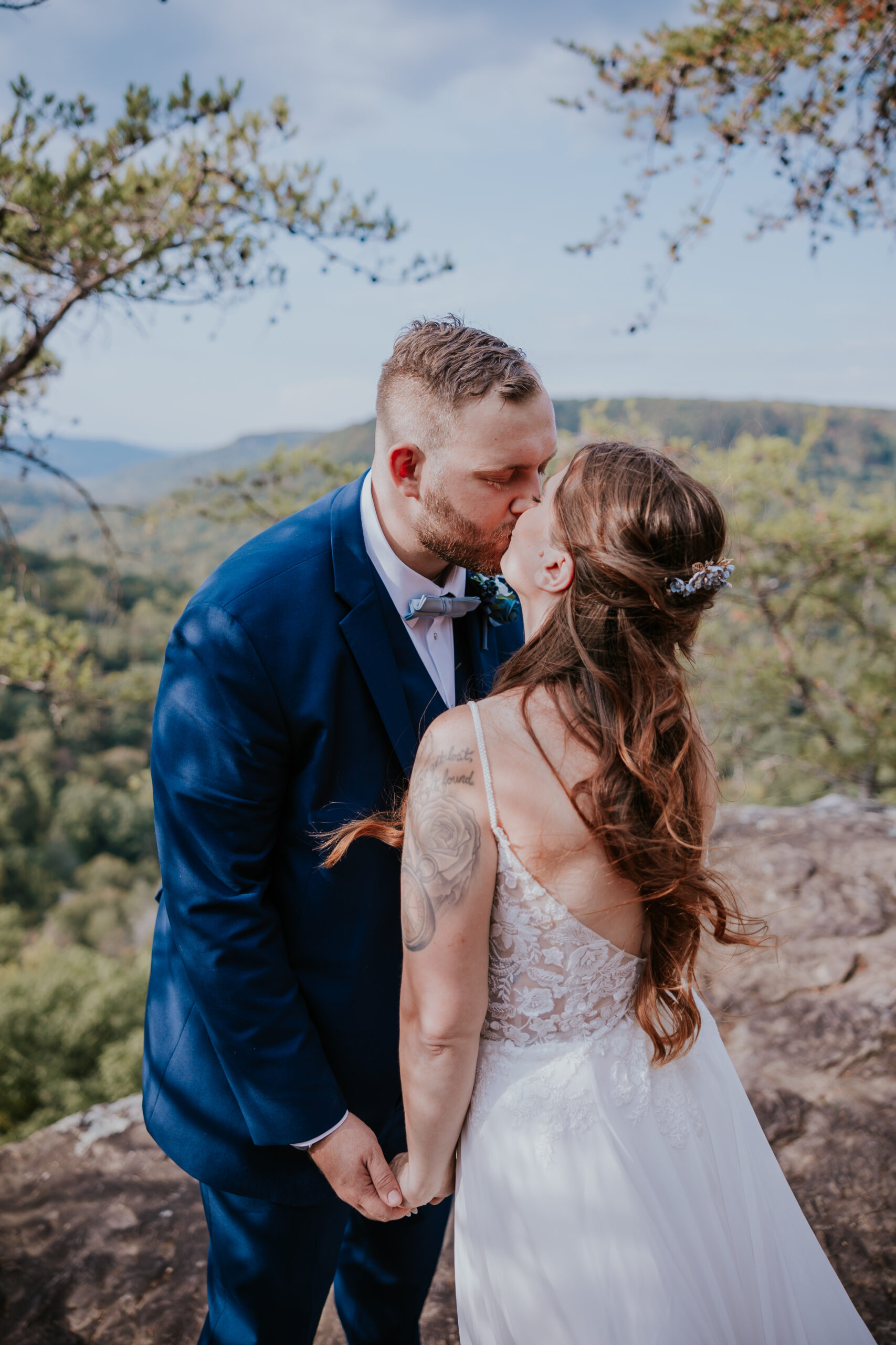 Full-length portrait of the couple on a rocky cliffside, with the bride’s dress flowing in the wind — a romantic twist on unique wedding ideas in a state park setting.