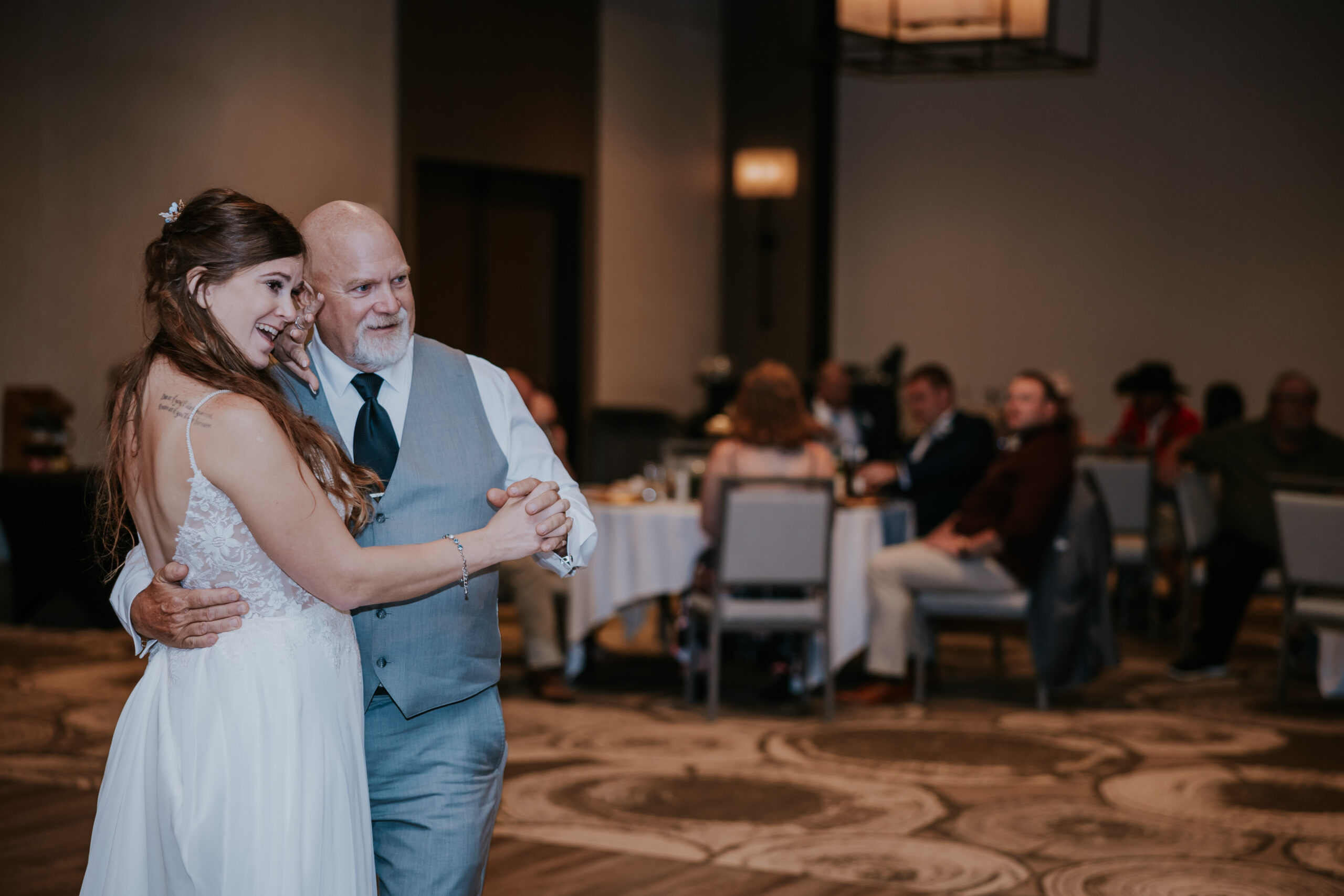Emotional moment as the bride shares a father-daughter dance during the wedding reception, surrounded by loved ones.
