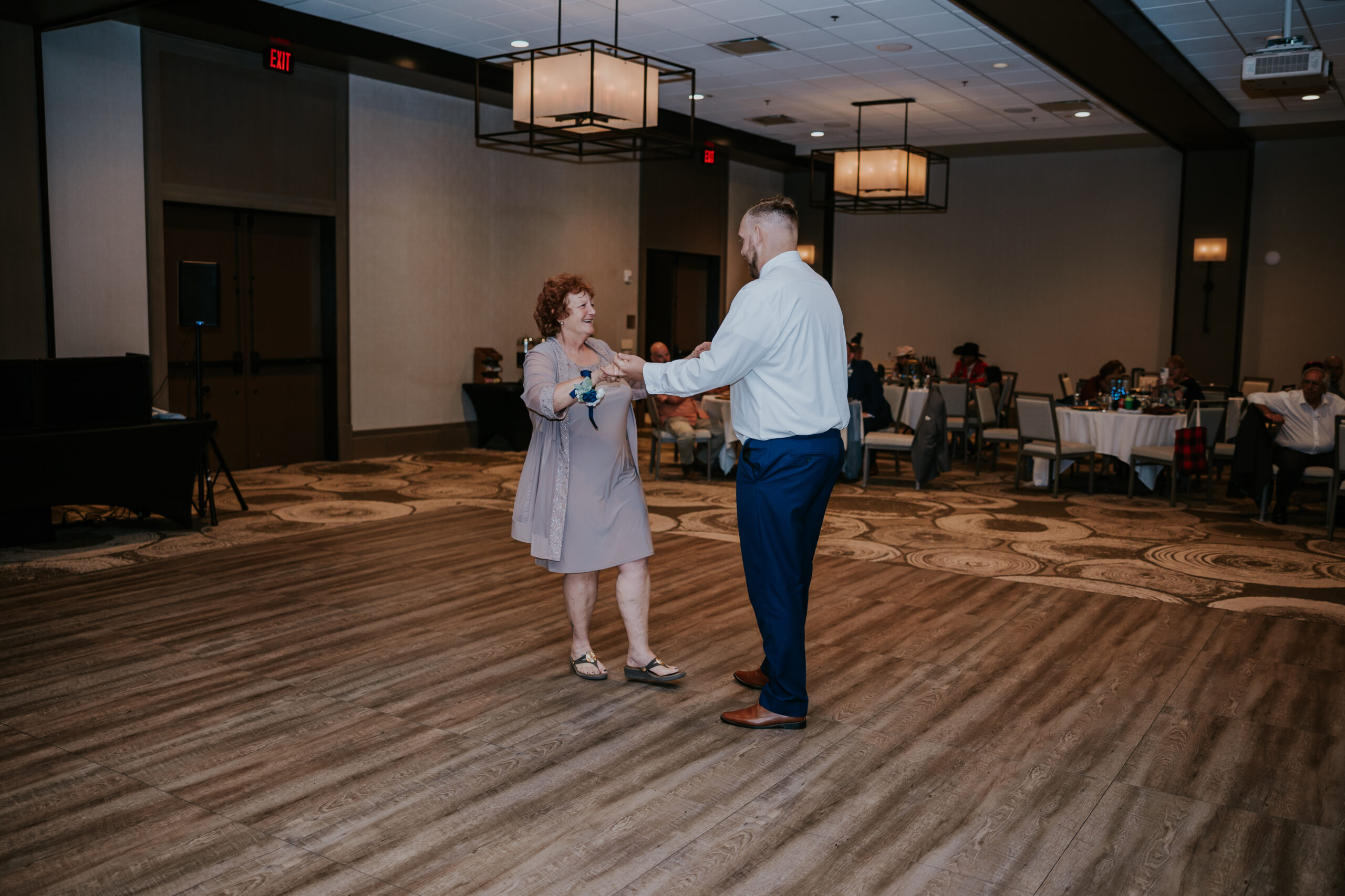 Groom twirls a guest across the dance floor during a lighthearted reception moment.