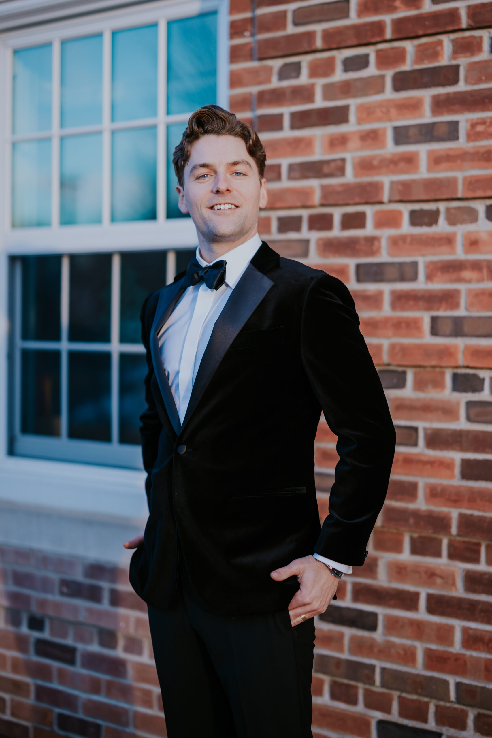 Groom posing confidently in a black velvet tuxedo jacket, captured by a wedding photographer in Minnesota.