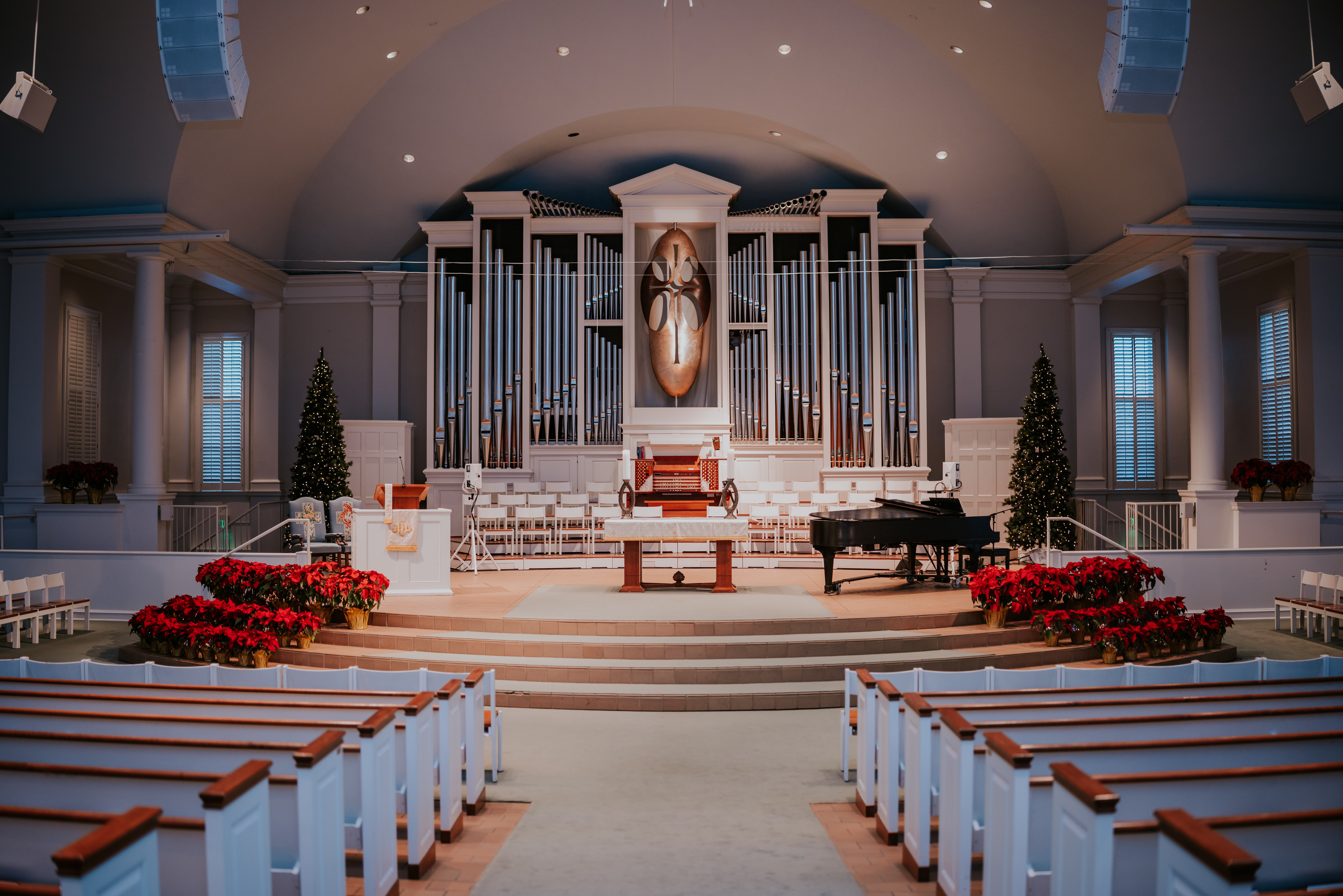 Empty church sanctuary decorated with Christmas trees and poinsettias before the ceremony.
