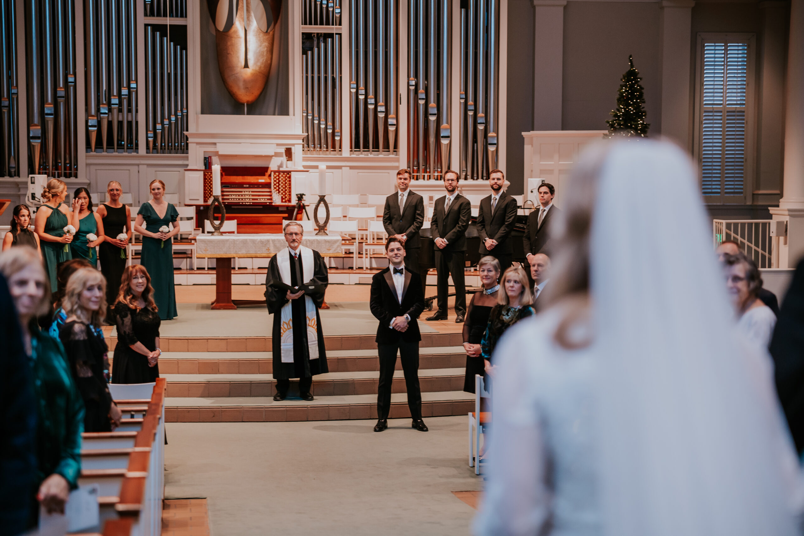 Groom watching his bride walk down the aisle, surrounded by wedding guests, captured by a wedding photographer in Minnesota.