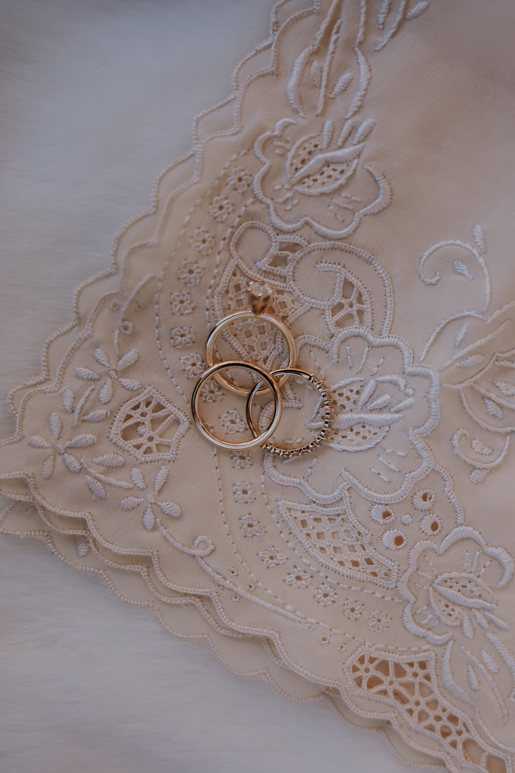 Gold wedding bands displayed on an embroidered handkerchief.
