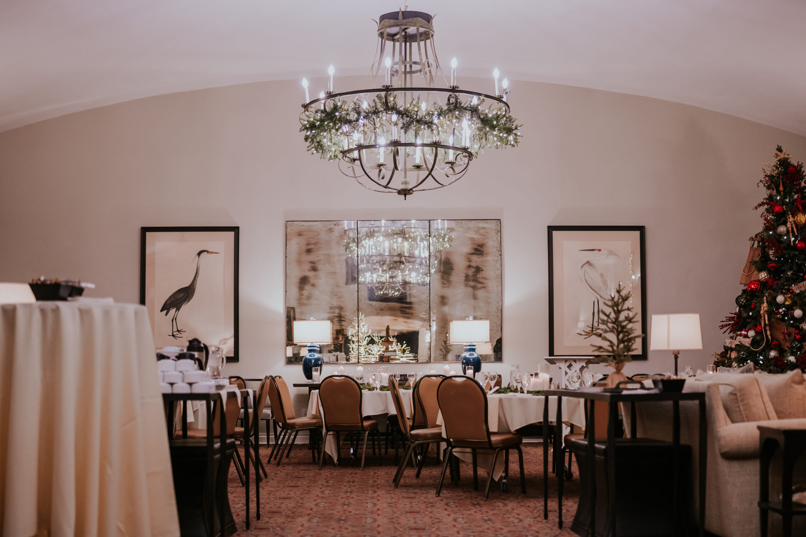 Wide view of the wedding reception room decorated with holiday greenery, chandeliers, and a Christmas tree.